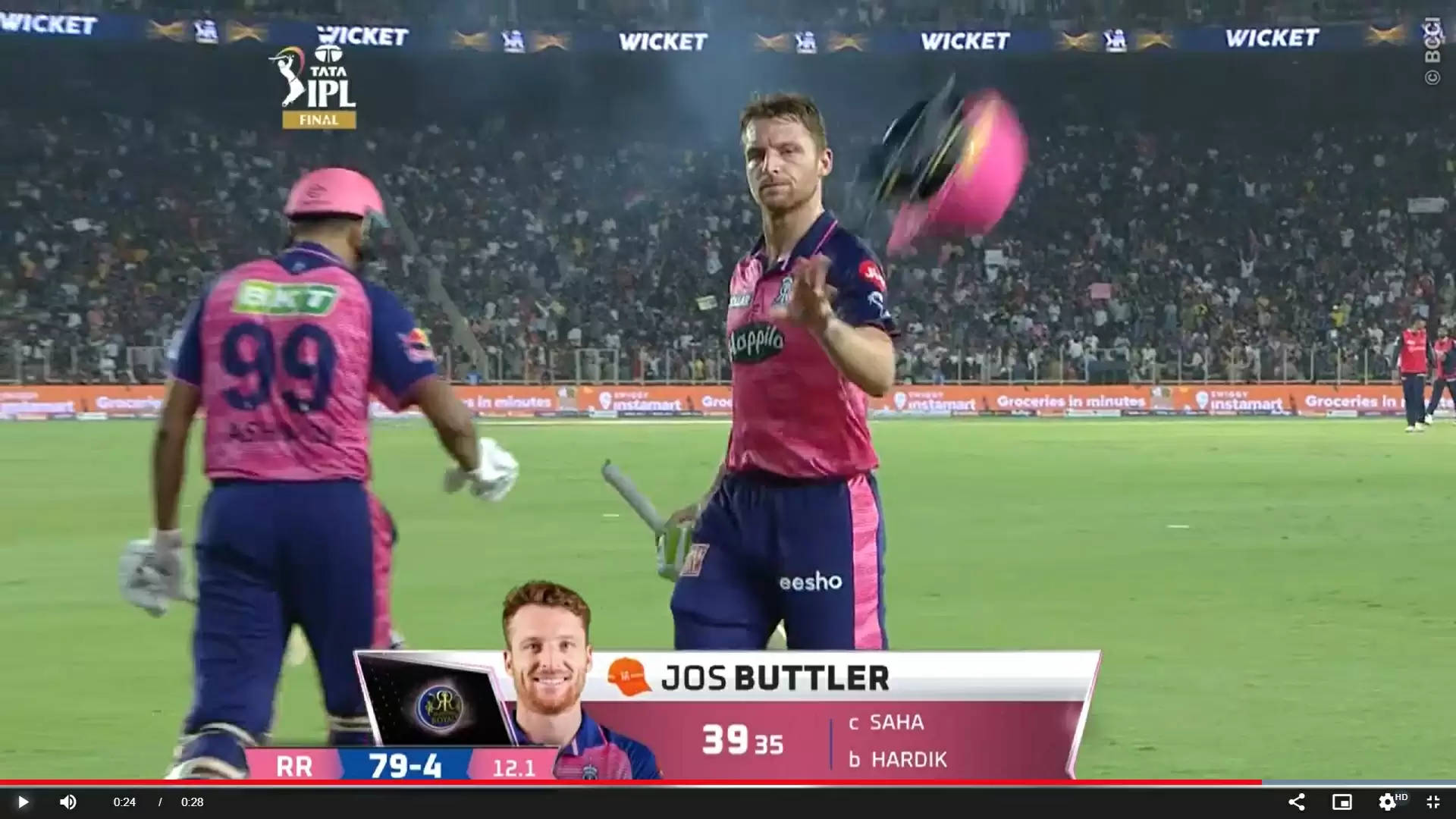 板球運動員 Jos Buttler 在夜間比賽中拋起粉紅色頭盔慶祝。
