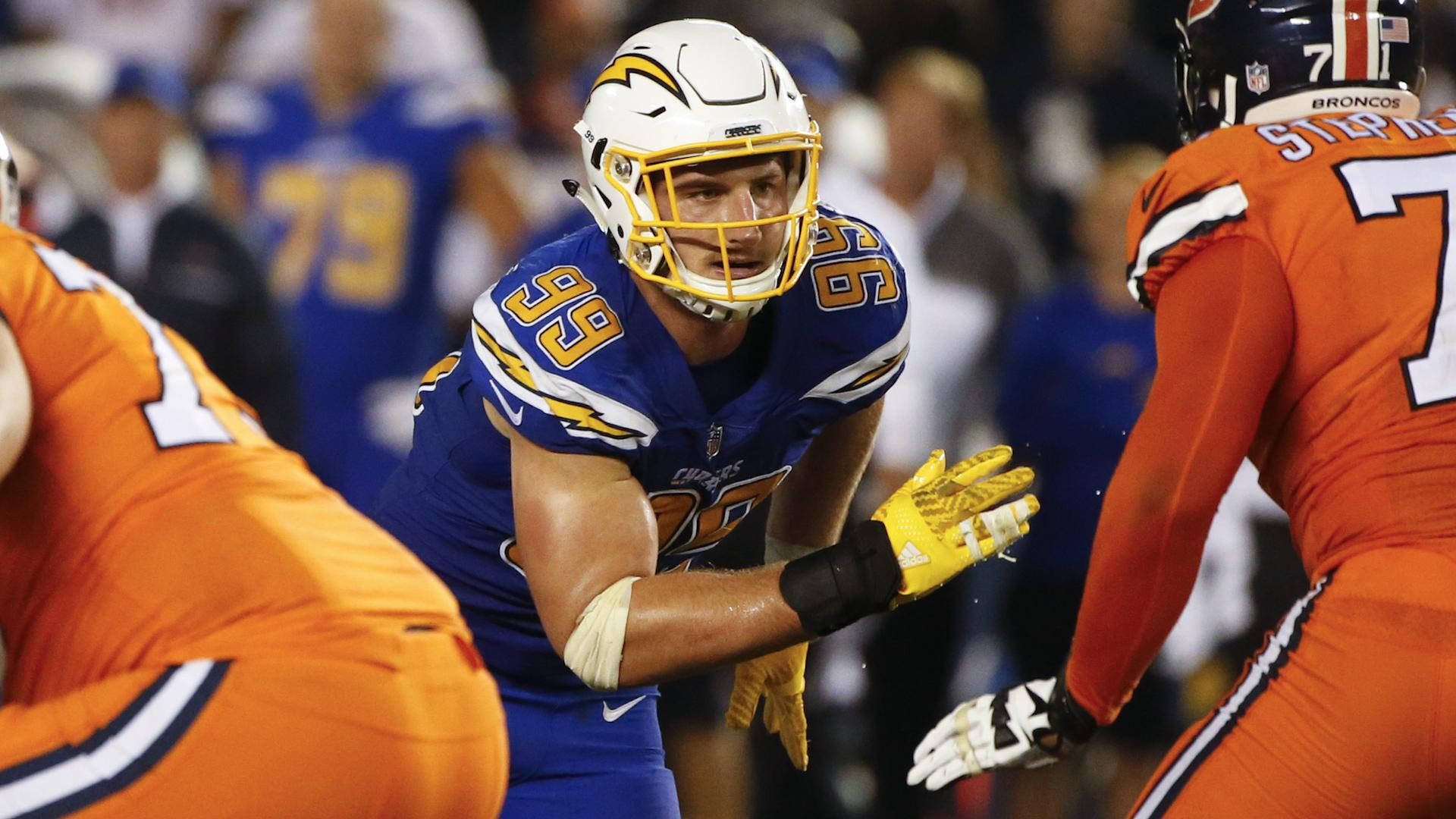 身穿藍黃色球衣的NFL足球員在夜間比賽中蹲下。