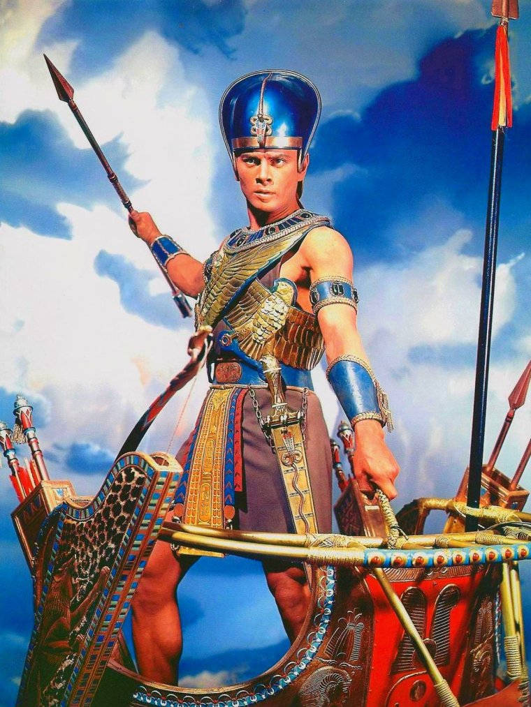埃及戰士身穿金色盔甲，在戰車上手持長矛，背景為多雲天空