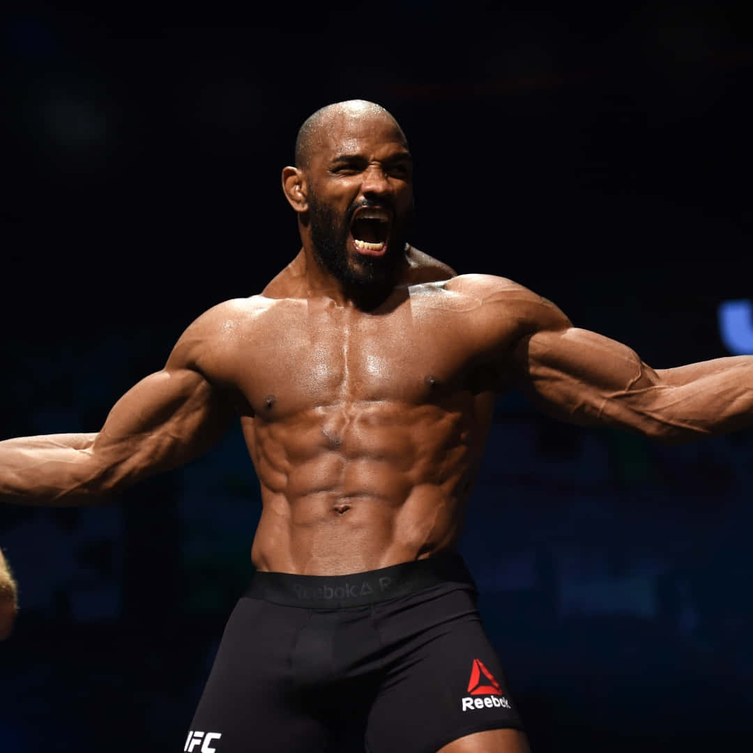 約爾·羅梅羅 UFC 213 TUF 終結賽公開訓練 壁紙 — 一個肌肉發達的鬥士在明亮的競技場燈光下張開雙臂，勝利地咆哮。