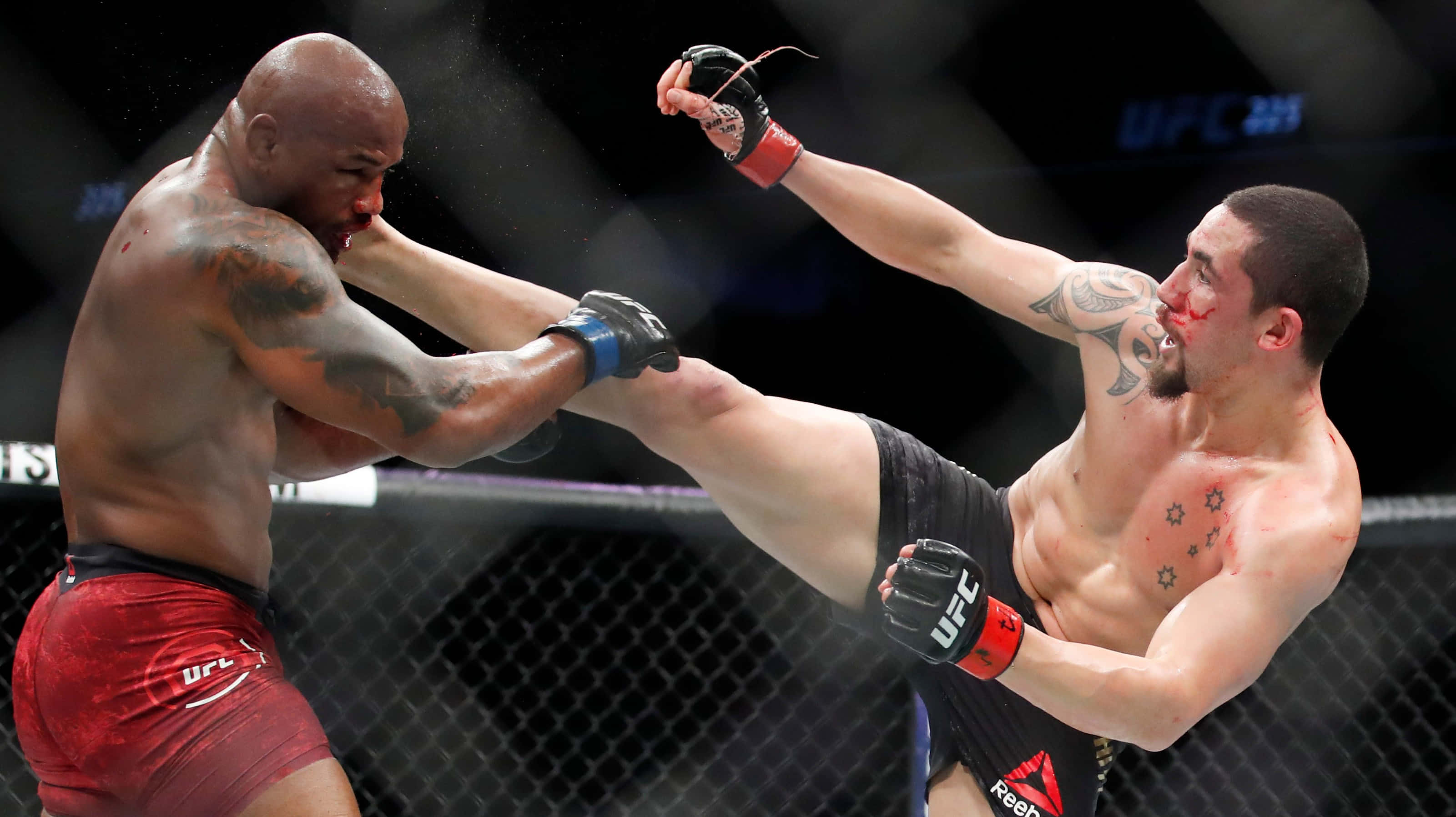 約爾·羅梅羅對決羅伯特·惠特克 UFC 225 壁紙 — 兩名MMA拳手在八角籠中交鋒，一人使出高踢，另一人阻擋，汗水在激烈時刻飛濺。