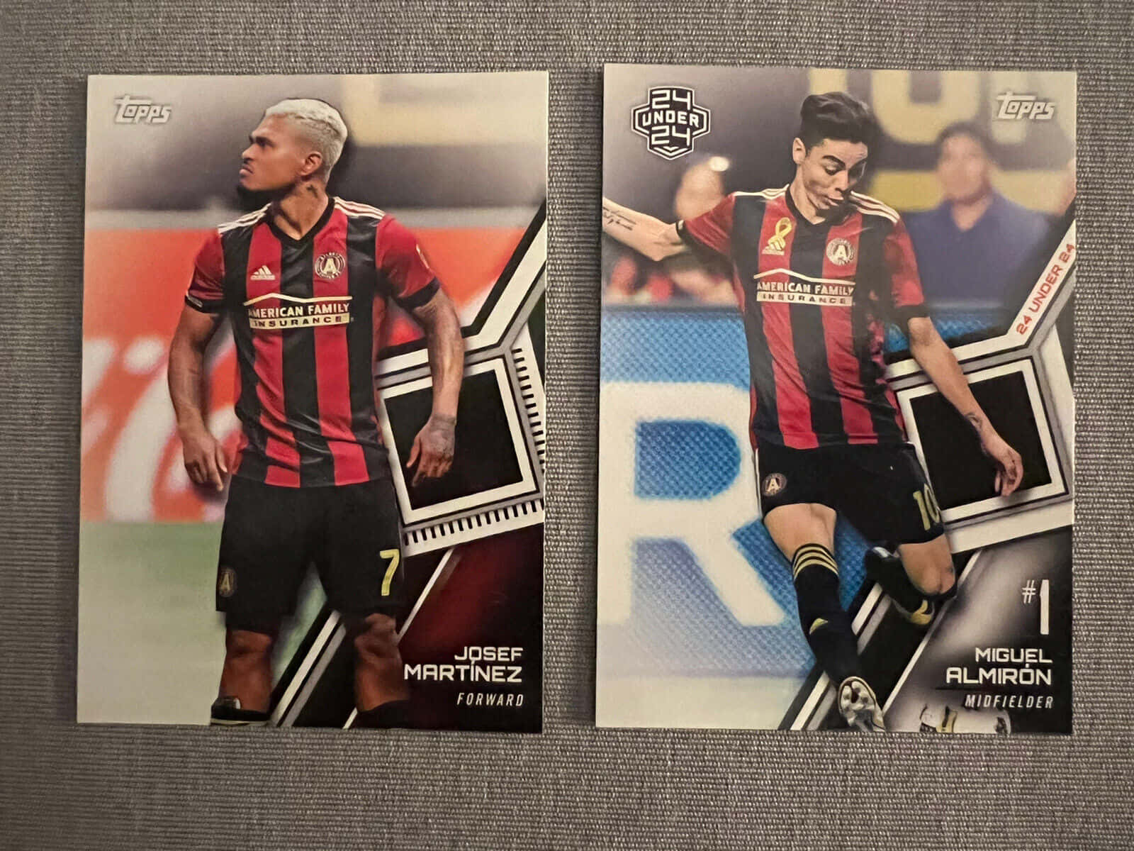約瑟夫·馬丁內斯與米歇爾·阿爾米龍賽場合作 壁紙 — 兩張Josef Martinez和Miguel Almiron的足球交換卡，身穿紅黑條紋球衣，展示在灰色紋理表面上。