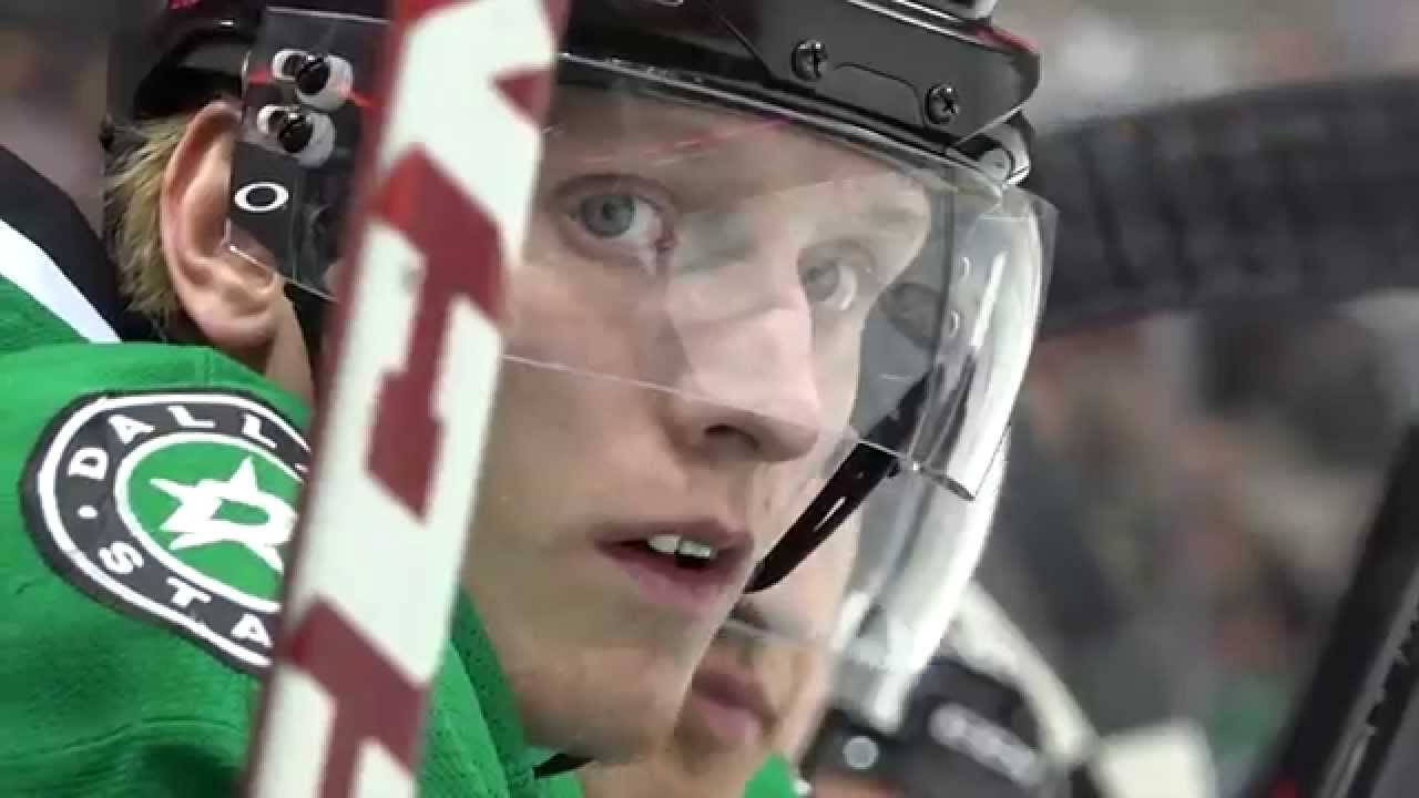 約翰·克林格伯格 NHL 球員放大特寫照片 壁紙 — 達拉斯星隊冰球球員的特寫，身穿綠色球衣和頭盔，透過面罩專注地凝視，球桿在前。