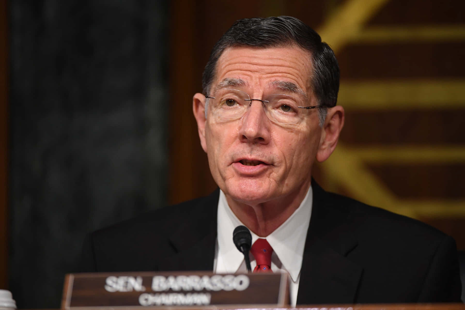 參議員Tom Barrasso在正式聽證會上發言，身穿西裝和紅色領帶。