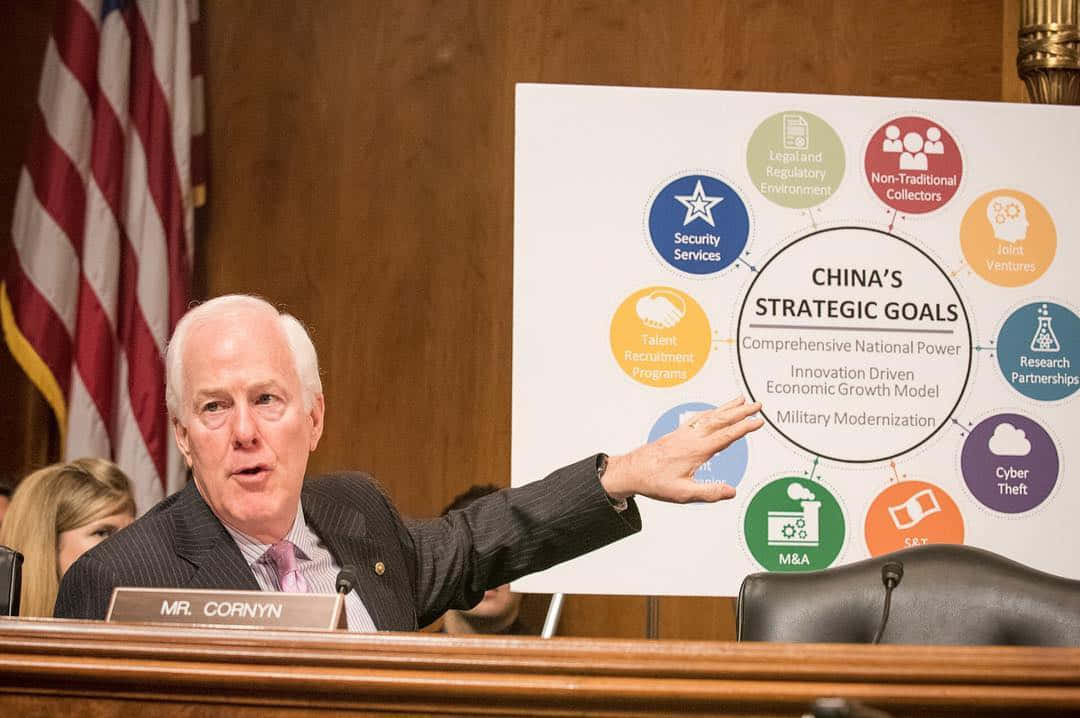 參議員約翰·科寧在國會聽證會上指向一張關於中國戰略目標的圖表。