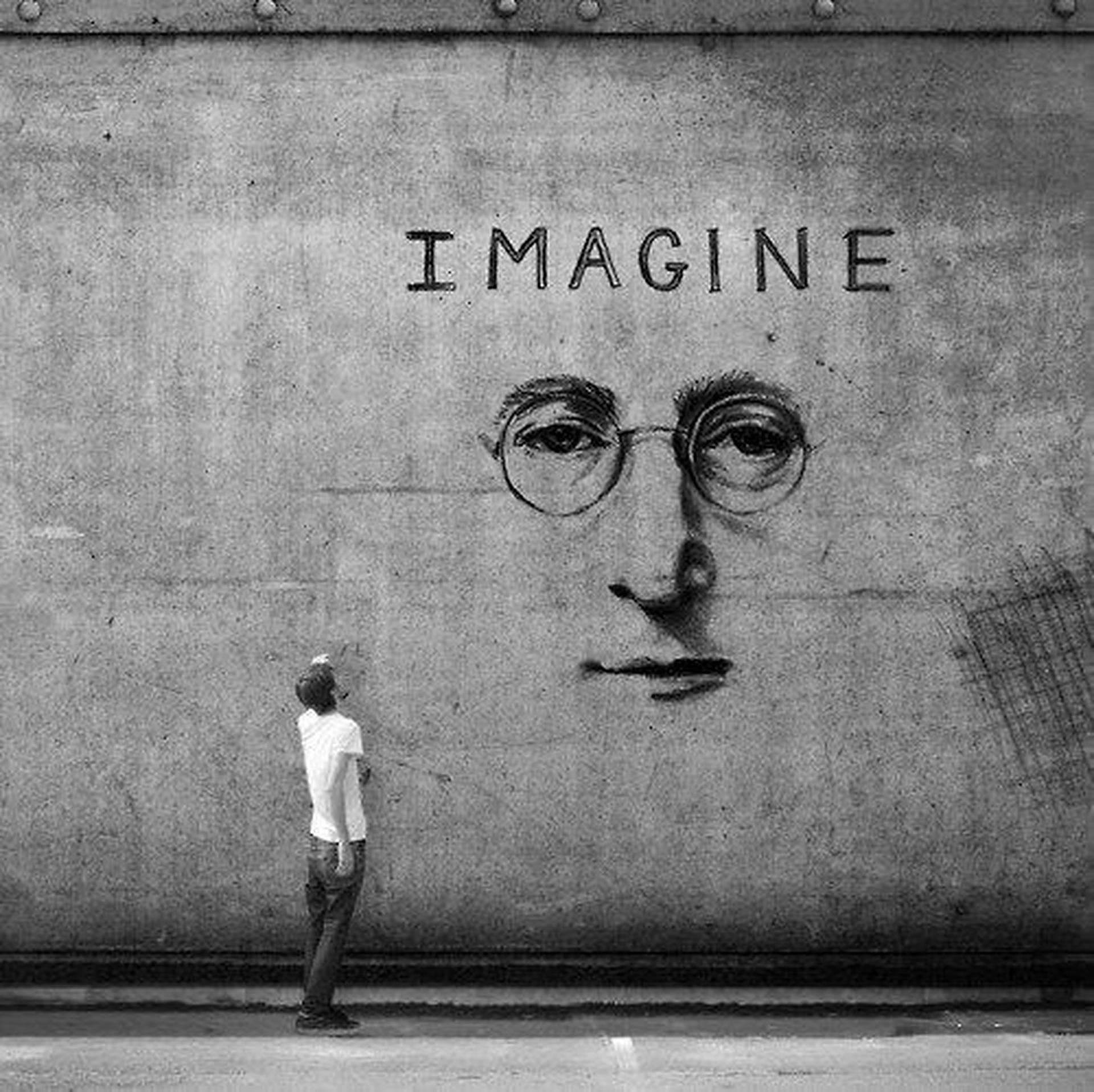 人抬頭看著帶有「IMAGINE」字樣的約翰·連儂大型壁畫 — 約翰·連儂 GIF 壁紙
