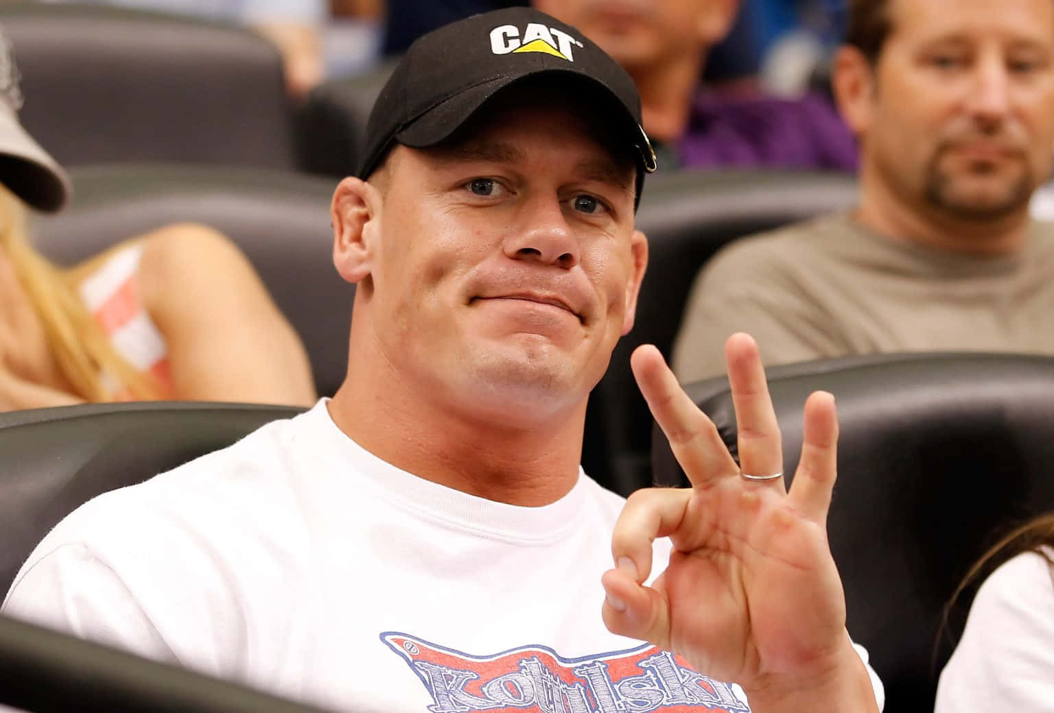 John Cena 桌布 壁紙 — 約翰·辛納在體育賽事中戴著CAT帽子微笑並比出和平手勢。
