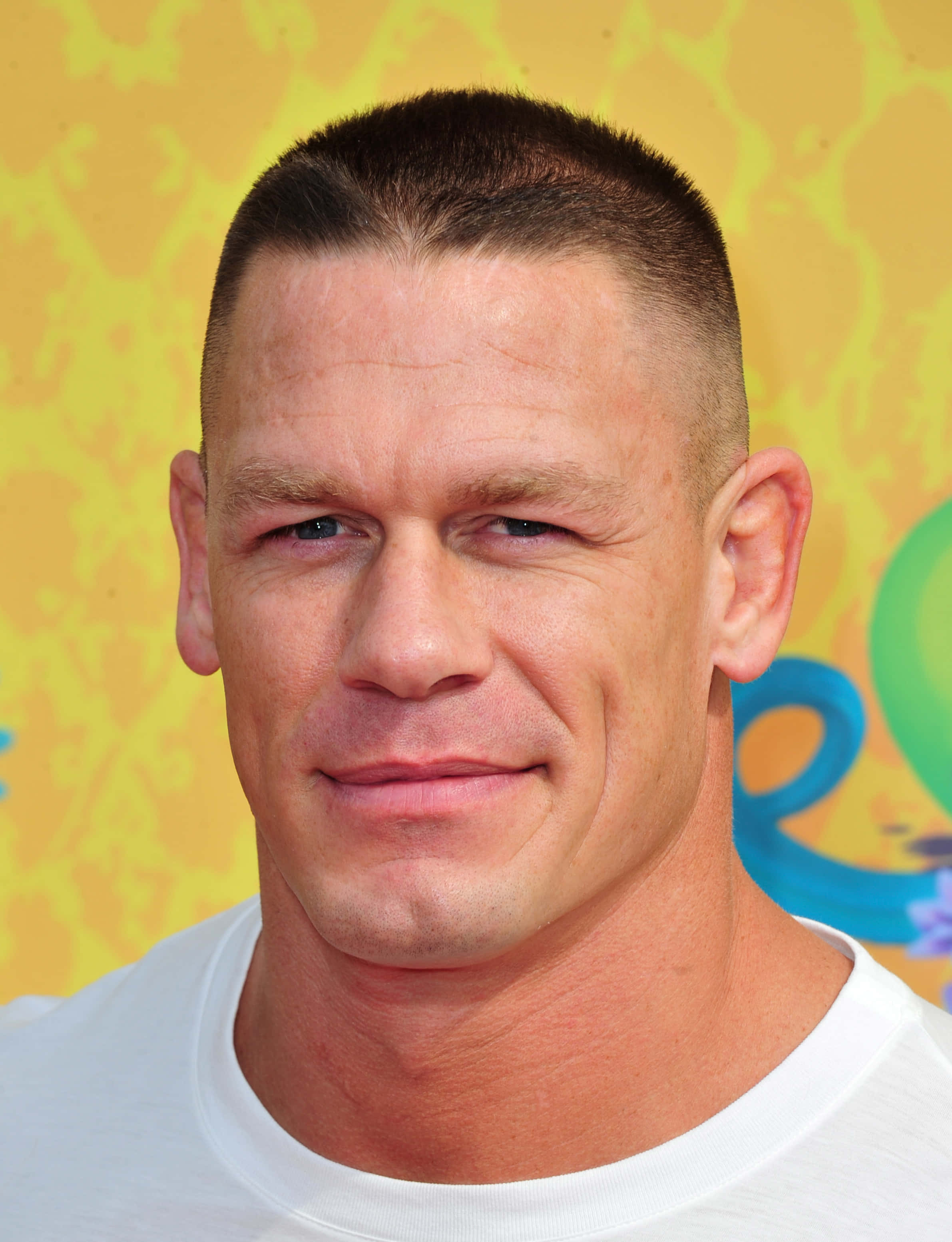 John Cena 桌布 壁紙 — 約翰·辛納的近距離肖像，在明亮的黃色圖案背景前微微微笑。