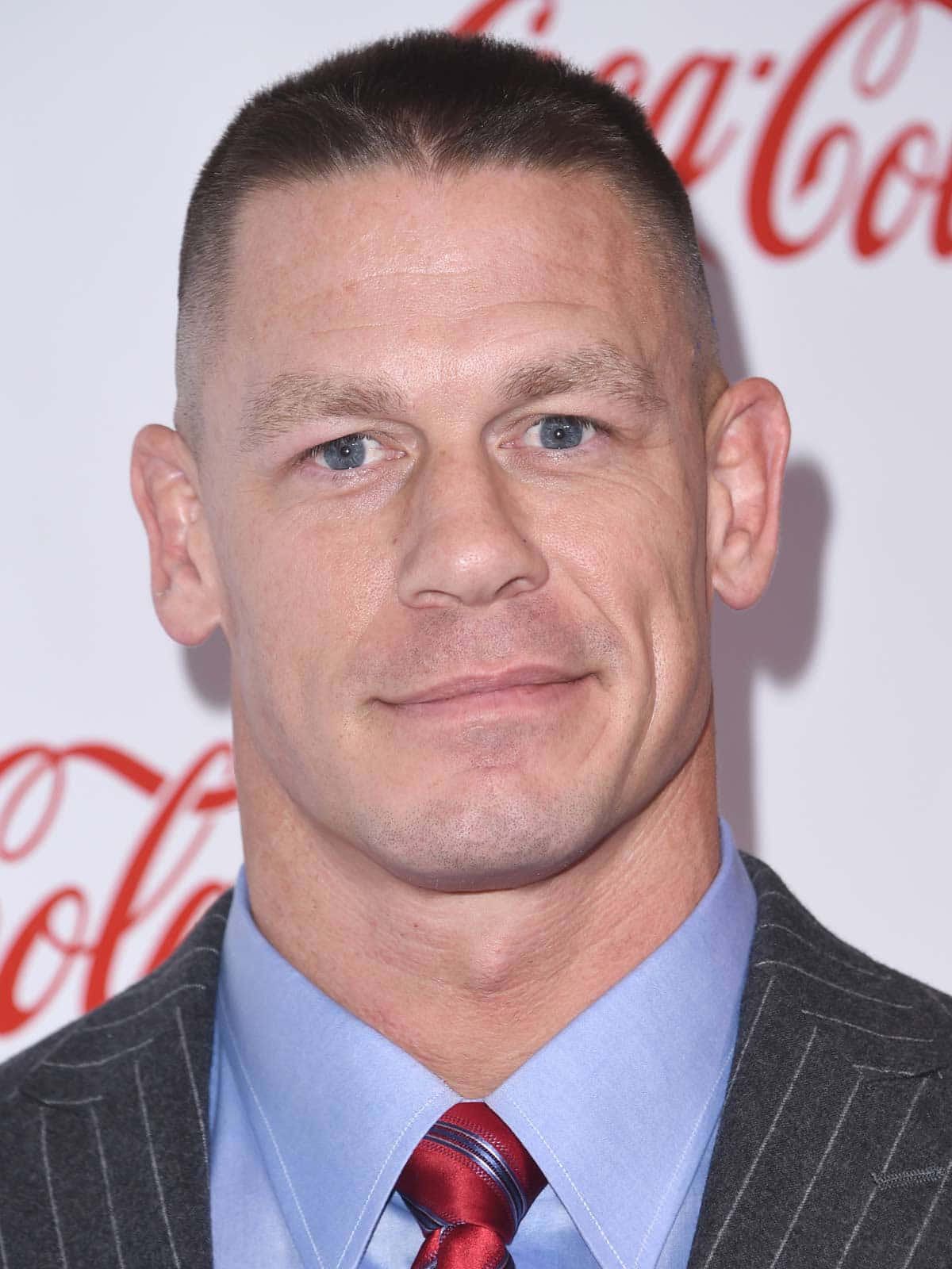 John Cena 桌布 壁紙 — 約翰·辛納身穿細條紋西裝和紅色領帶，以可口可樂品牌背景的特寫肖像。