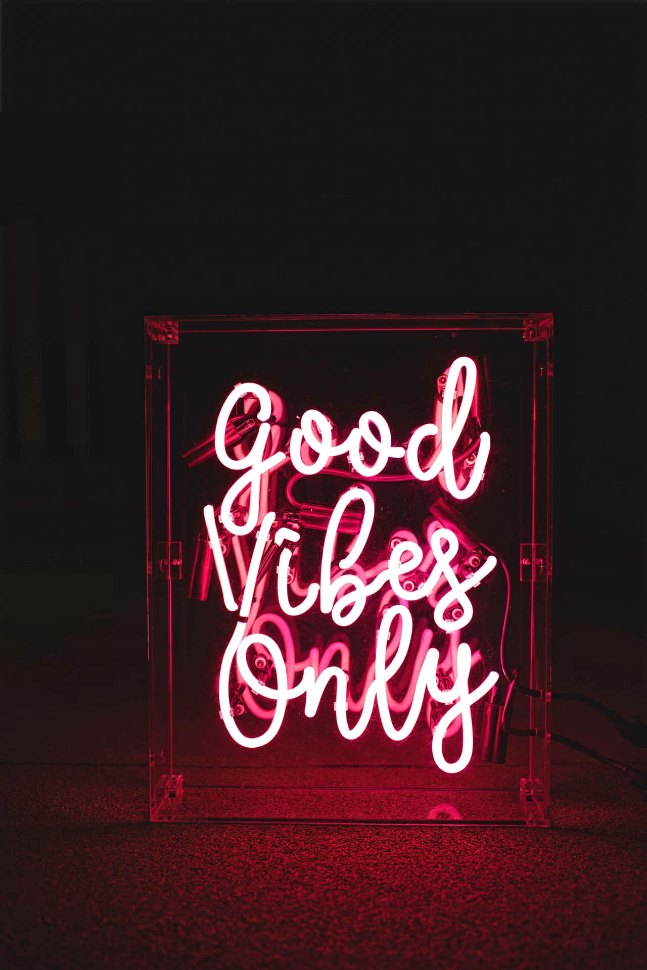 粉紅色霓虹燈牌，在黑暗房間中以草書寫着 Good Vibes Only。