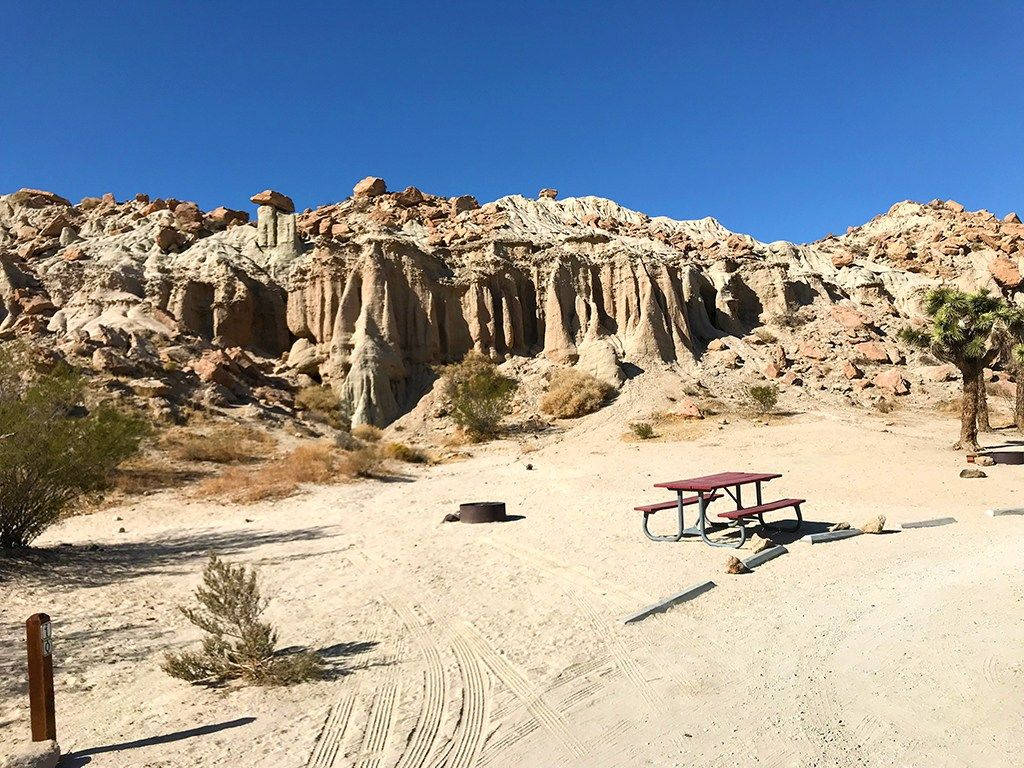 藍天下有野餐桌和岩石 formations 的沙漠營地