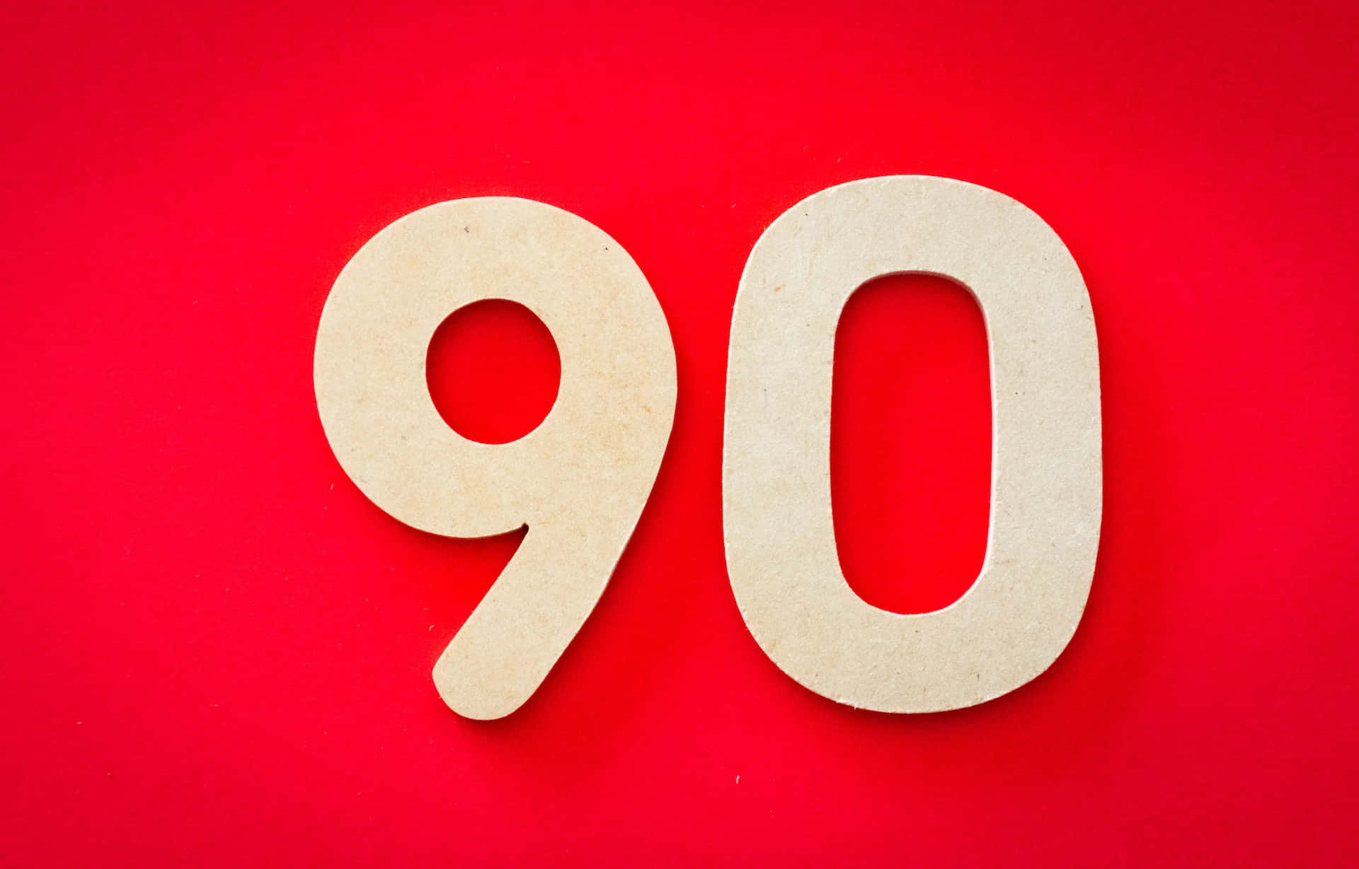 紅底灰字數字90圖像 壁紙 — 大型米色鏤空數字九十在鮮紅色背景上大膽矗立。