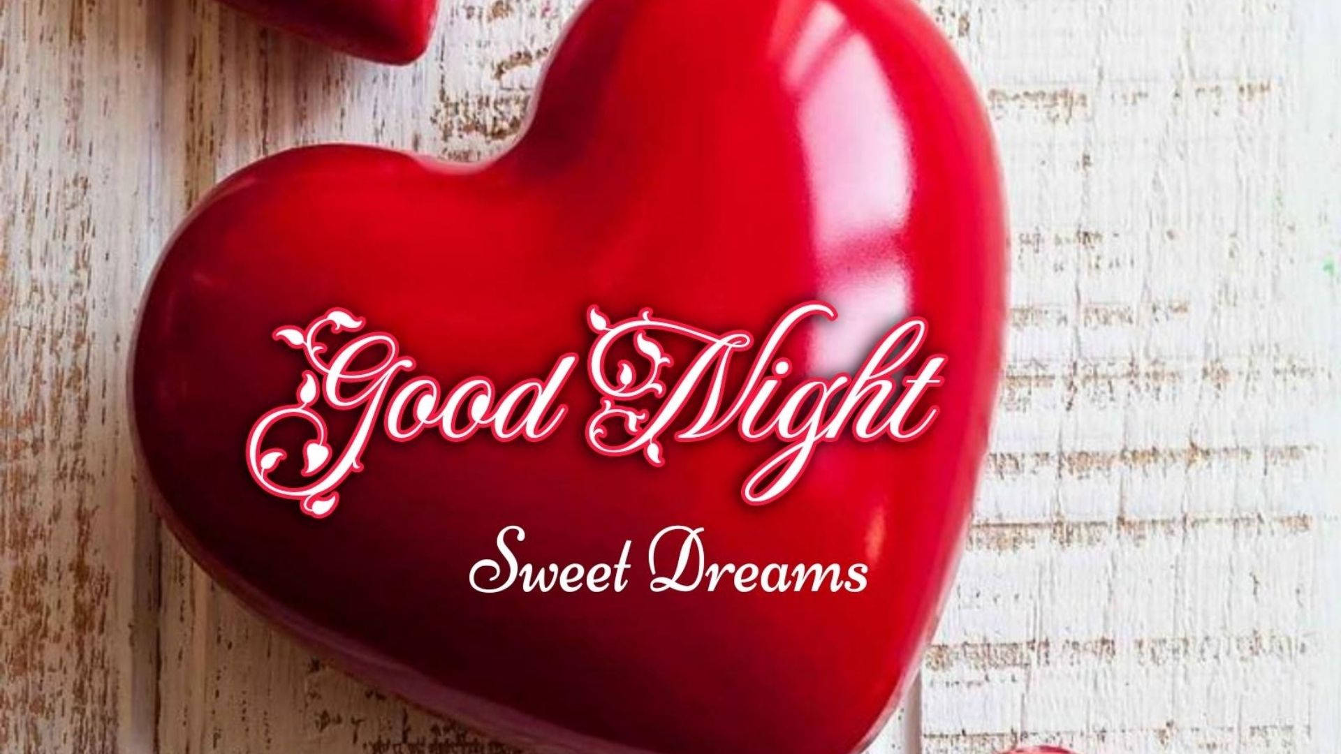 紅心上的甜夢祝福 壁紙 — 一個帶有白色「Good Night Sweet Dreams」字樣的亮面紅色心形物體，放置在經風化的白色木質表面上。