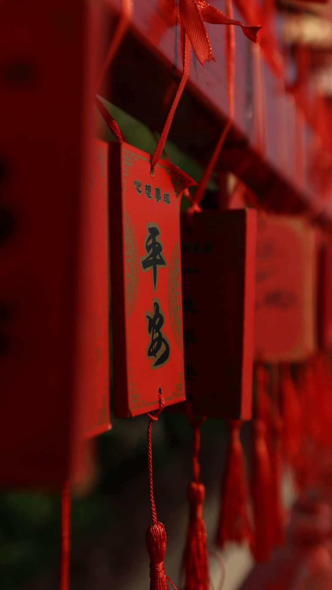 紅春聯懸掛 壁紙 — 鮮紅色祈福標籤的特寫，上面有黑色中文字，用紅絲帶和流蘇綁成一排懸掛。