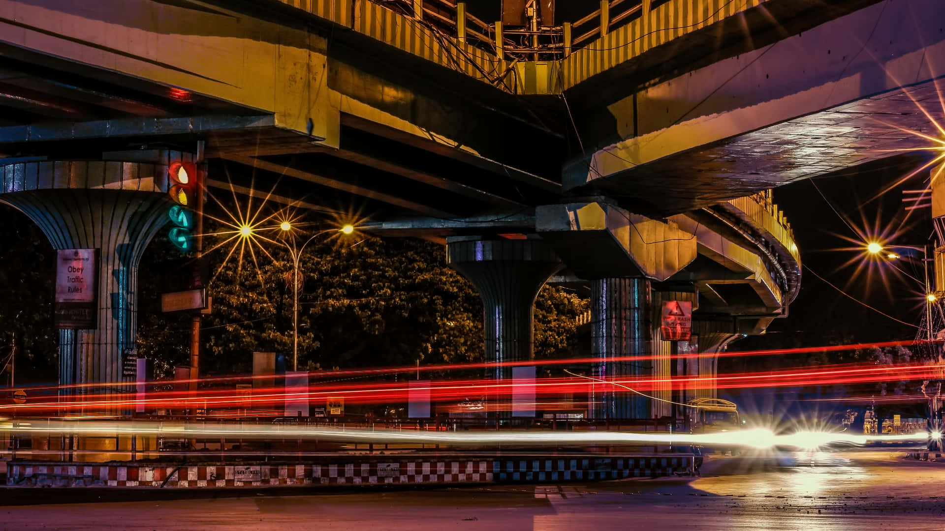 夜間城市景觀，在照明立交橋下行駛的汽車留下的光跡。