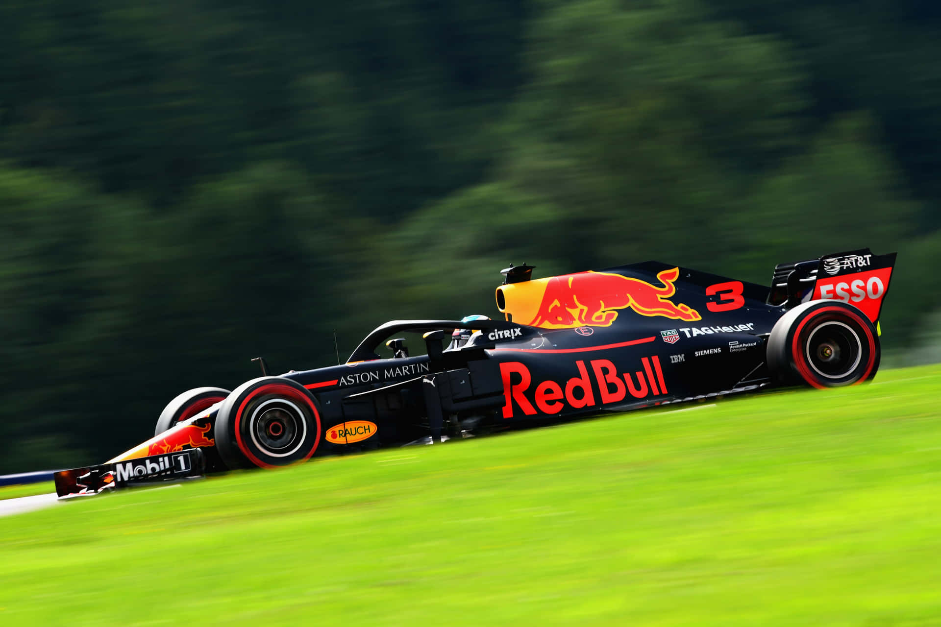 紅牛F1賽車在綠色賽道上以森林為背景比賽。
