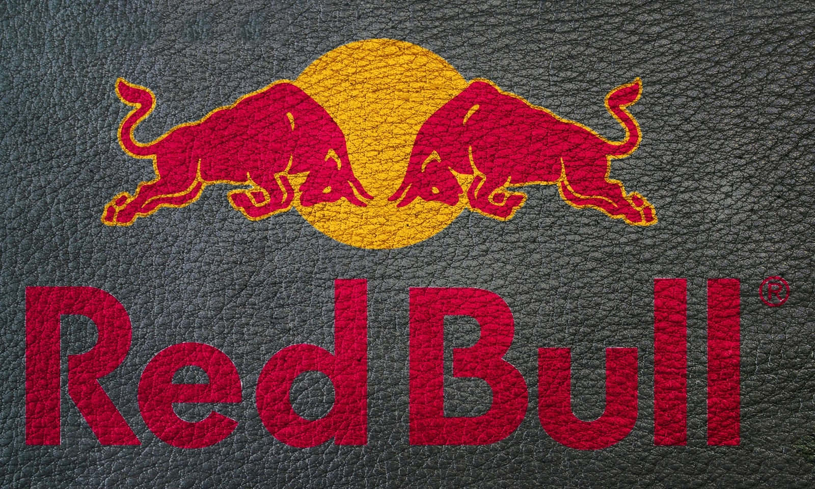 深灰色皮革背景上的 Red Bull 標誌，帶有兩頭紅色公牛和黃色太陽。