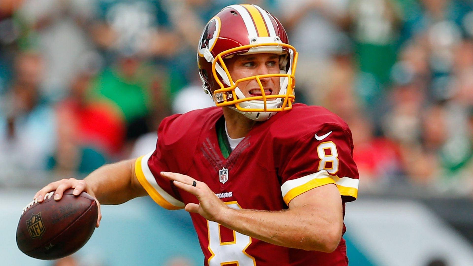 紅皮隊8號 Kirk Cousins 壁紙 — 一位專注的NFL四分衛，身穿紅色球衣背號8，在日間比賽中準備擲出橄欖球。