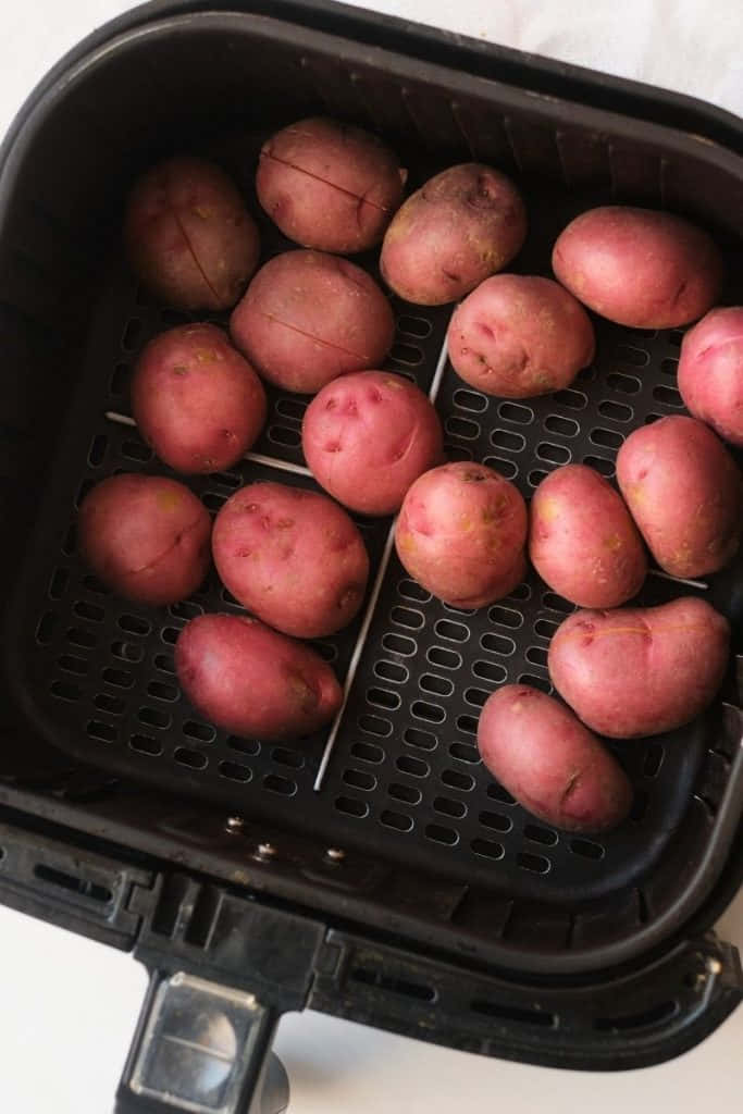 Red Potatoes 桌布 壁紙 — 紅皮馬鈴薯表皮劃上刻痕，整齊排列在黑色氣炸鍋籃子中，準備烹調。