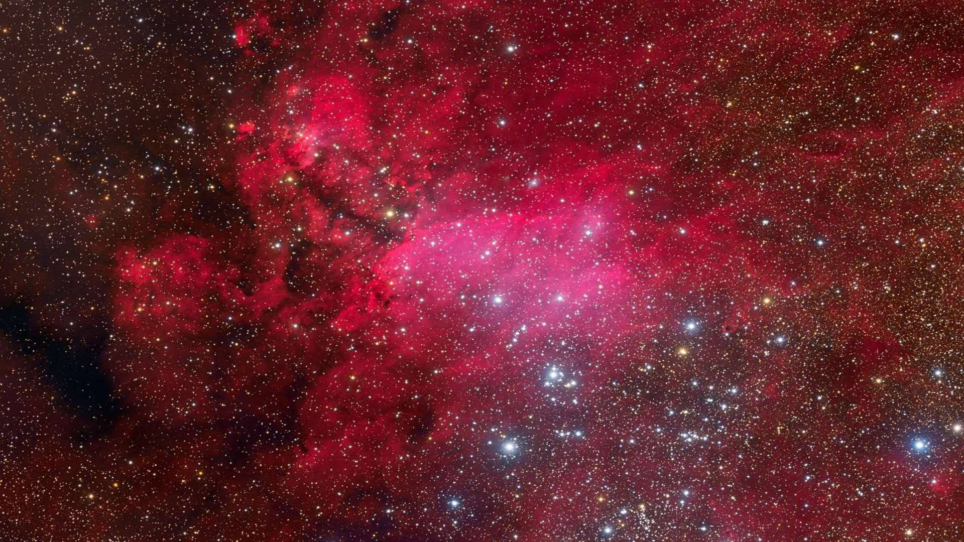 紅粉星系 壁紙 — 令人嘆為觀止的景象，一個充滿活力的紅色星雲在黑暗的宇宙虛空中閃耀著無數星星。