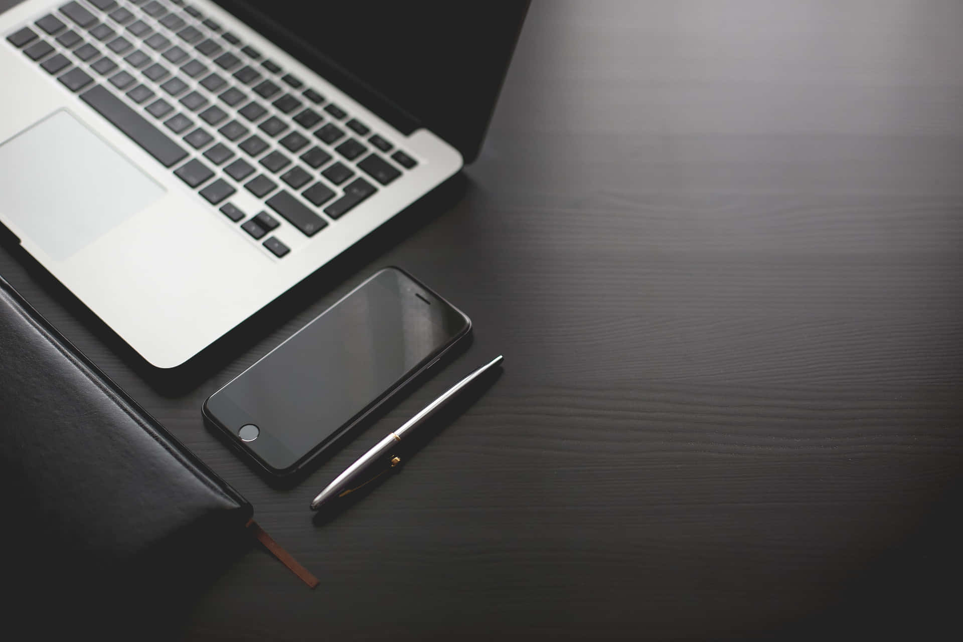 深色木桌上的銀色筆記型電腦、智能手機和筆 — 美學 MacBook 壁紙 壁紙