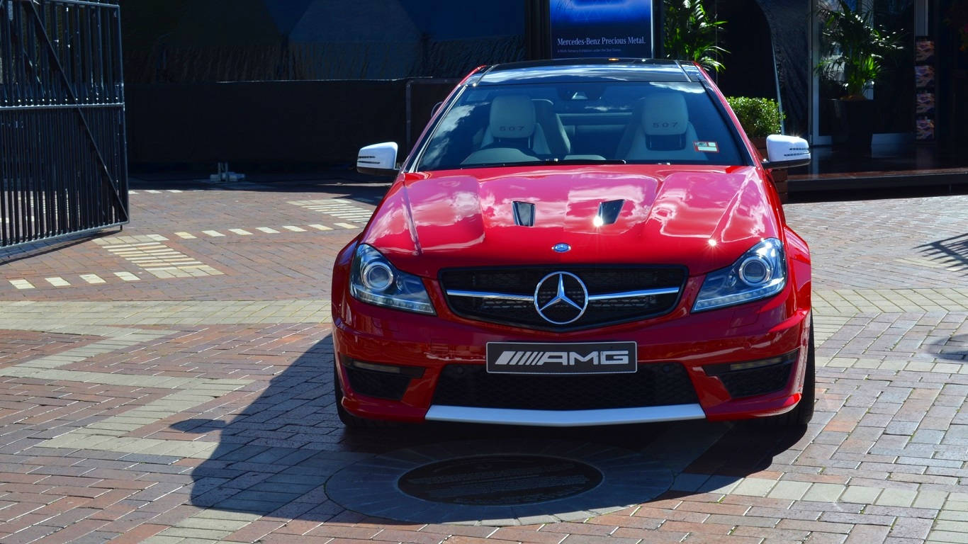 紅色 Mercedes-AMG 跑車停泊在磚砌路面上，在明亮的陽光下。