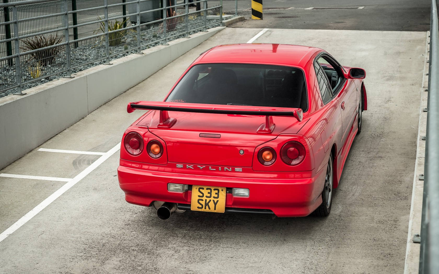 紅色日產Skyline GT-R停在混凝土停車場。