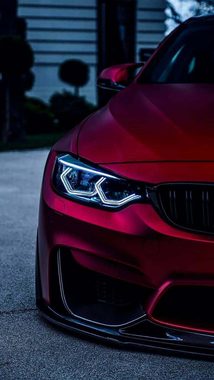 光澤紅色BMW跑車在黃昏時停車，車頭燈亮起。