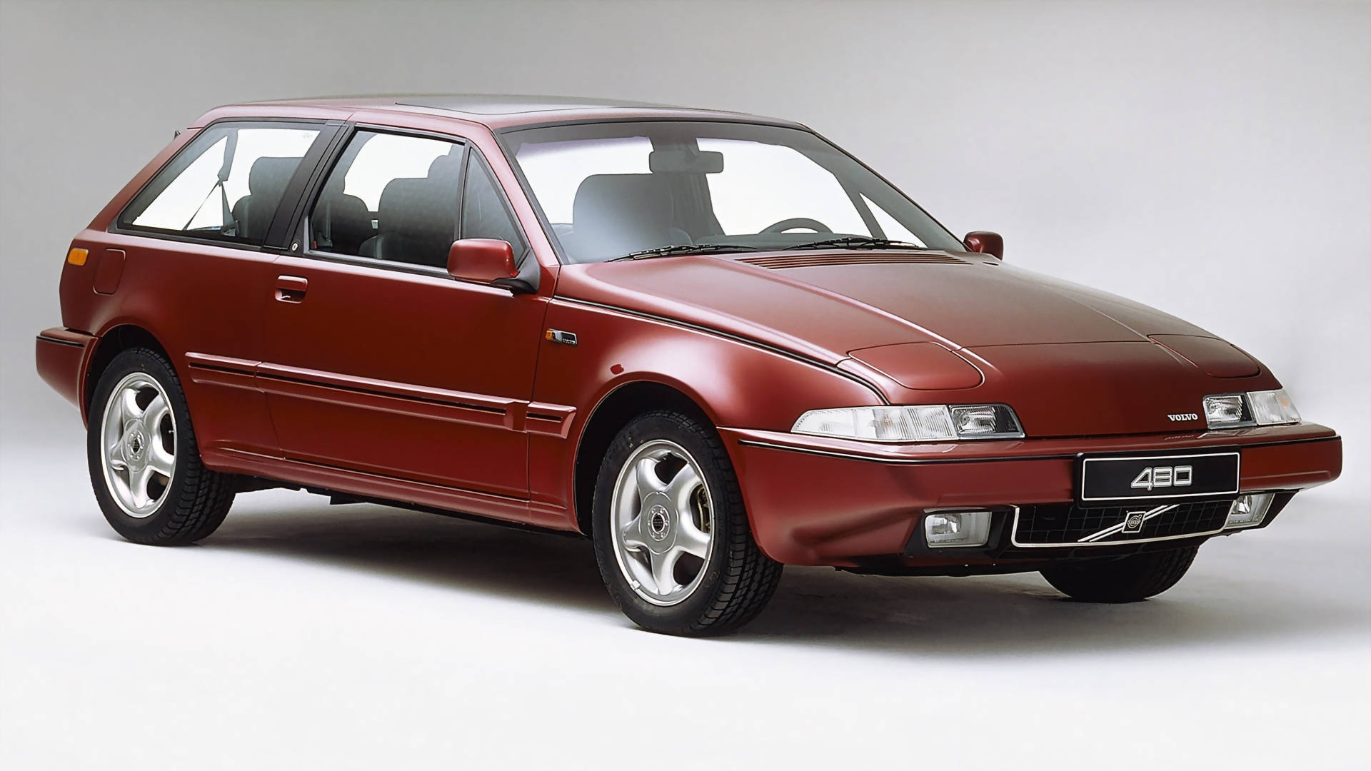 紅色480系列Volvo iPhone相片 壁紙 — 一輛時尚的栗色富豪430掀背車在白色背景的攝影棚燈光下閃閃發光。