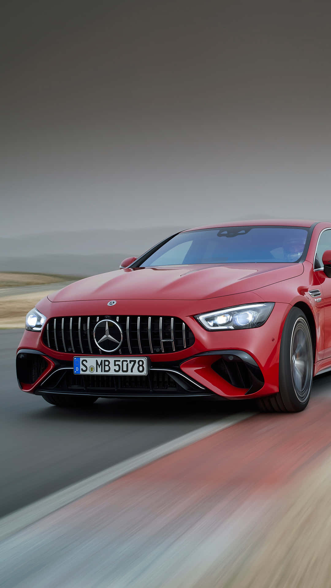 紅色AMG GT-R速度主題安卓壁紙 壁紙 — 一輛充滿活力的紅色 Mercedes-AMG GT R 在模糊的道路上奔馳，動態模糊效果強調了其動力和流線型設計。