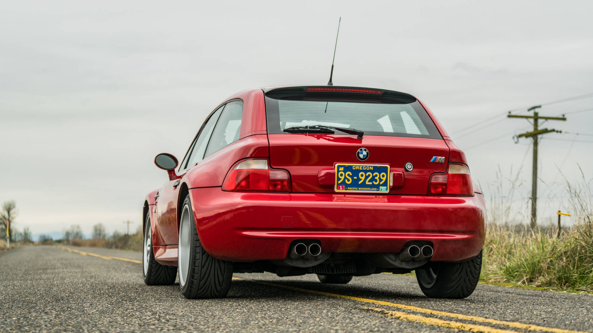 紅色BMW M3停泊在郊區路上，天空多雲。
