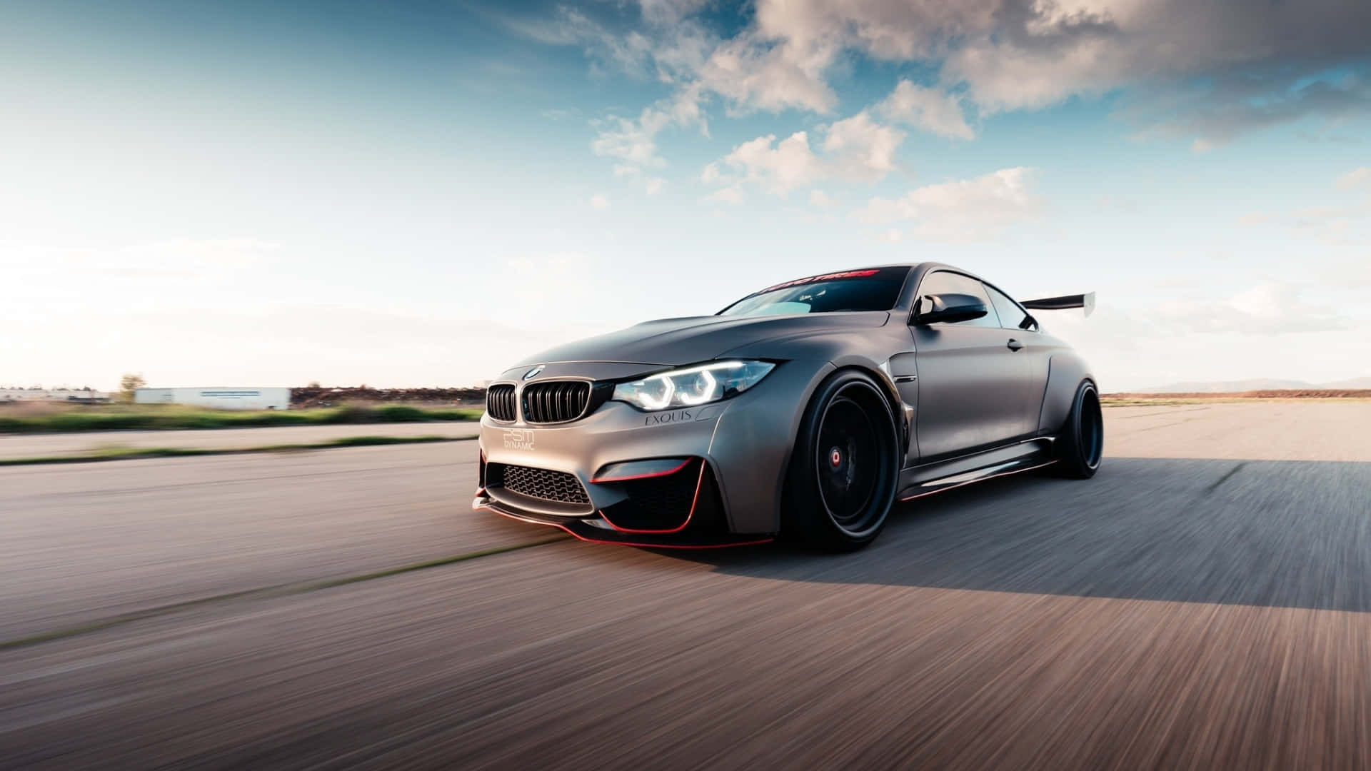 銀色BMW M4跑車在日落時分於沙漠跑道上飛馳。
