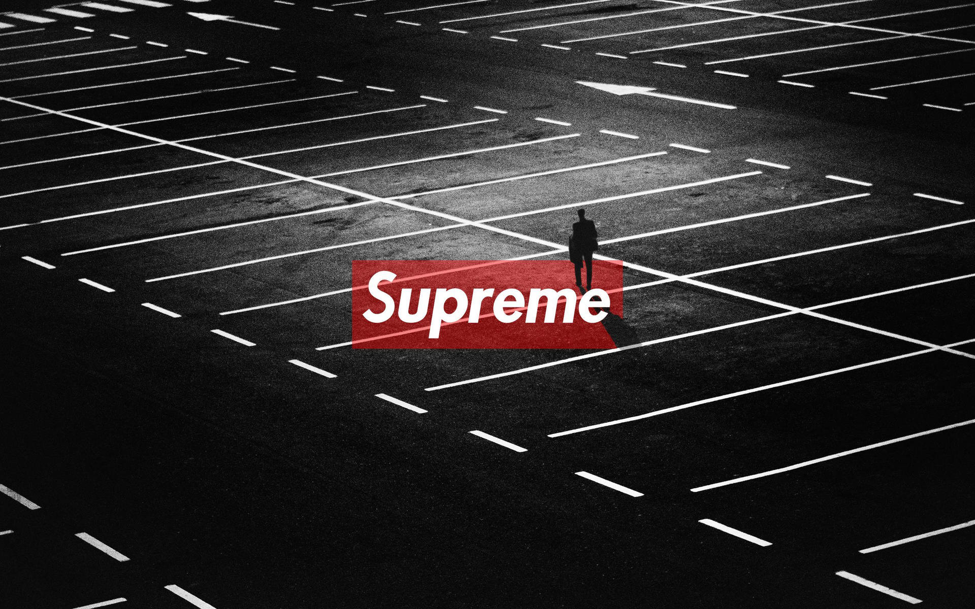 一個孤獨的人站在空曠的停車場，帶有紅色Supreme標誌。