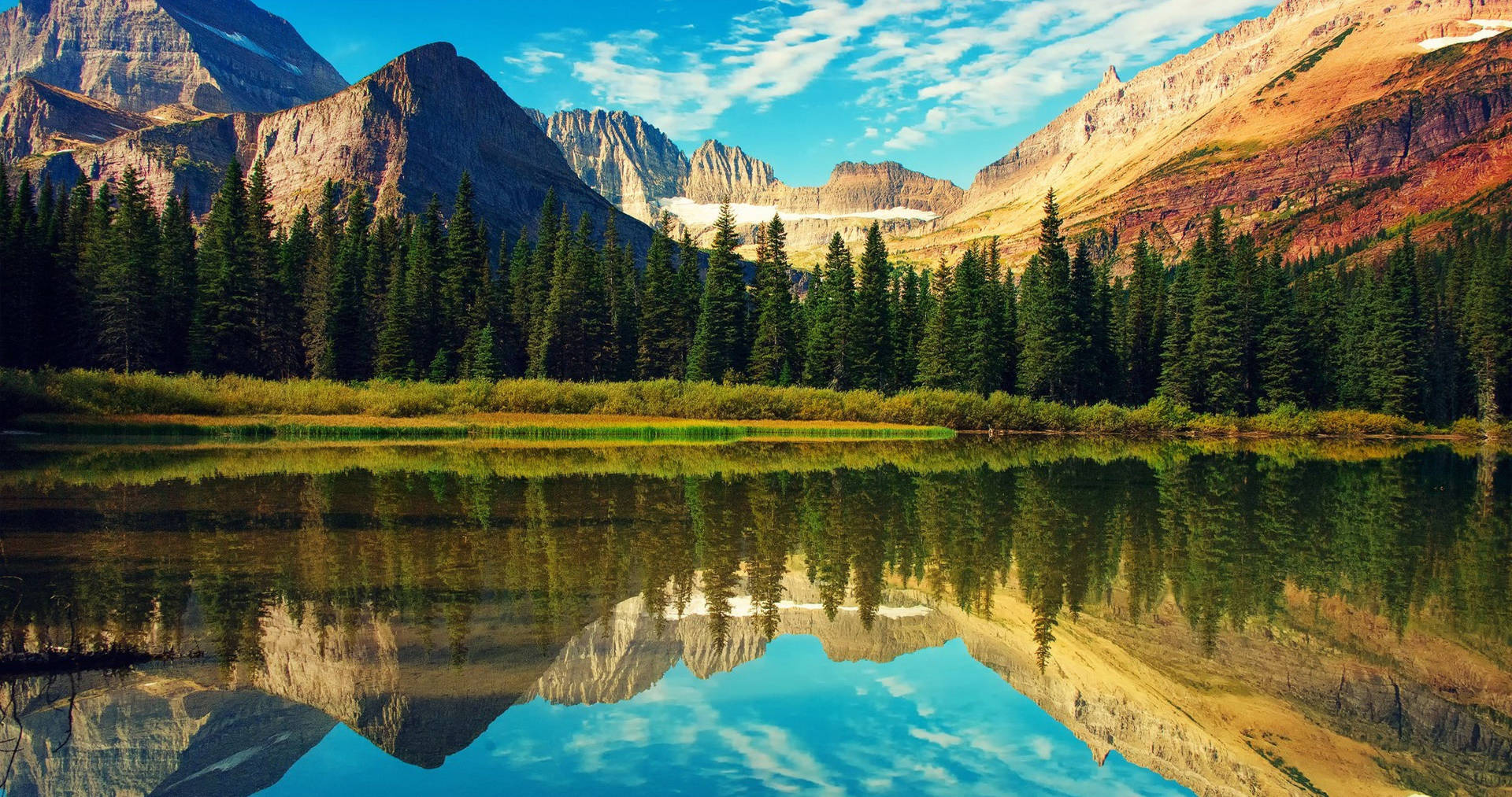 山湖映照出高聳的山峰和常綠樹木，在藍天下。