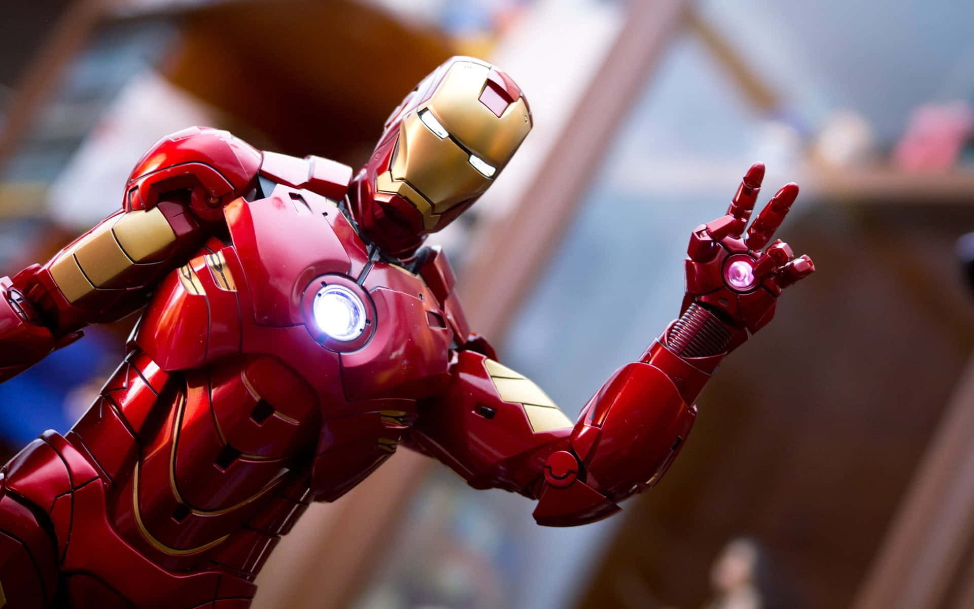 Iron Man Action Figures 桌布 壁紙 — 紅色和金色鐵甲奇俠套裝的特寫，帶有發光的弧形反應器和斥力手勢。