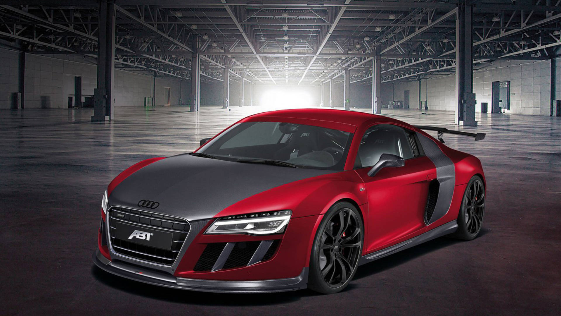 紅色奧迪跑車 壁紙 — 一輛時尚的紅黑色ABT Audi R8跑車在廣闊的工業倉庫中，在戲劇性的燈光下閃閃發光。