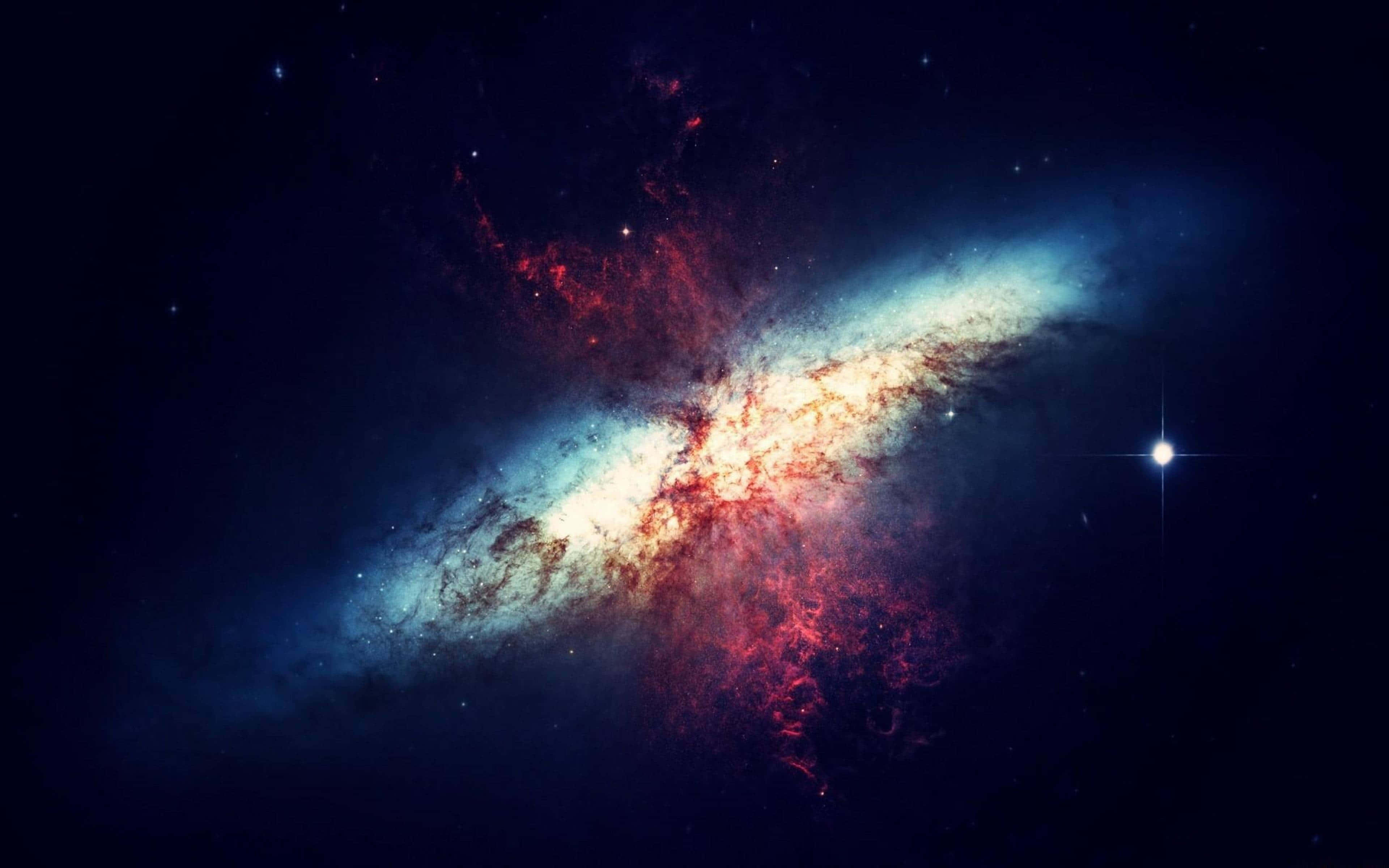 紅色宇宙之謎 壁紙 — 一個充滿活力的螺旋星系，在繁星點點的宇宙虛空中旋轉著紅色和藍色的星雲。
