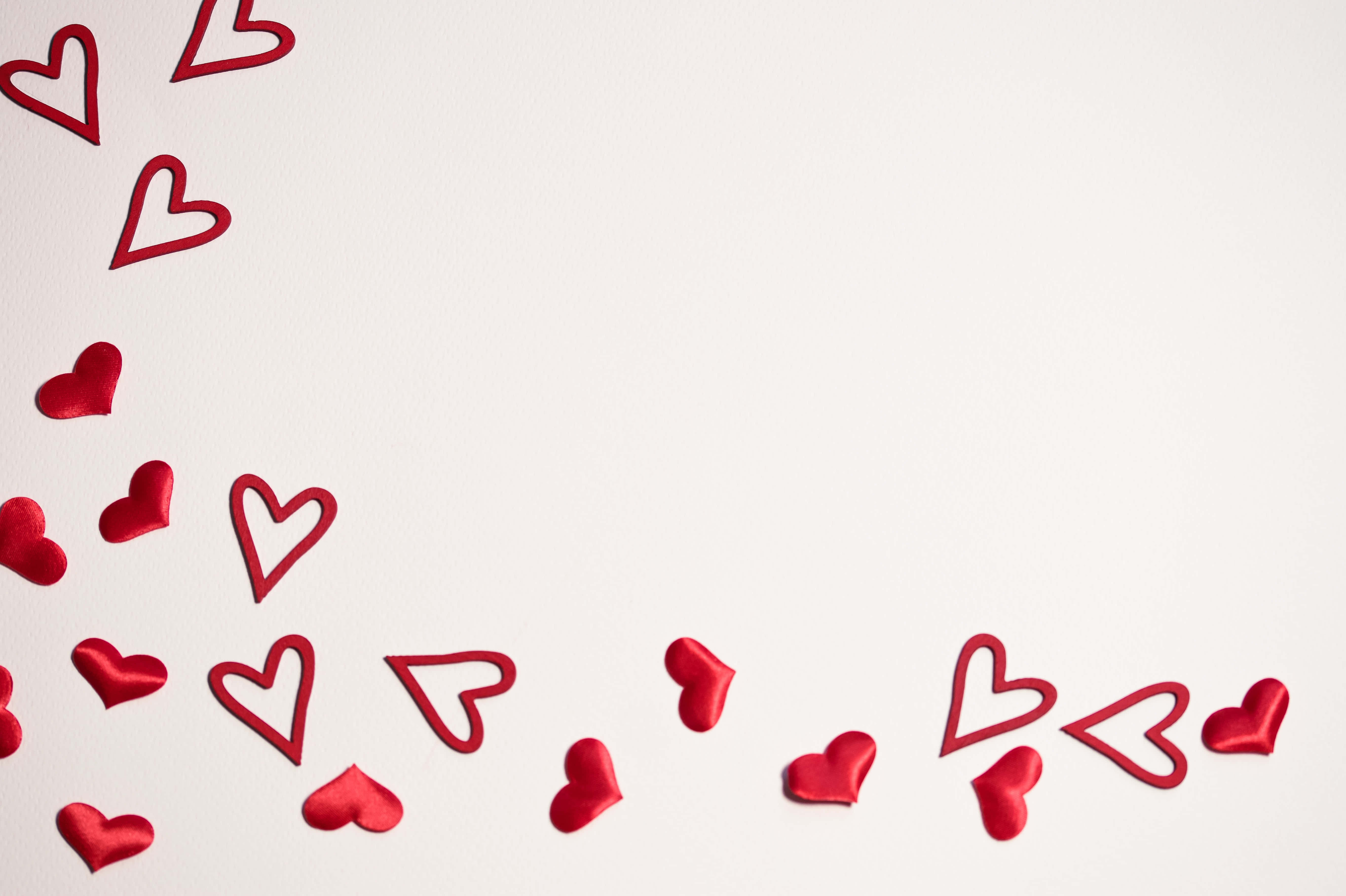 Cute Hearts 桌布 壁紙 — 紅色心形剪紙散落在純白色紋理背景的左下角和右下角。