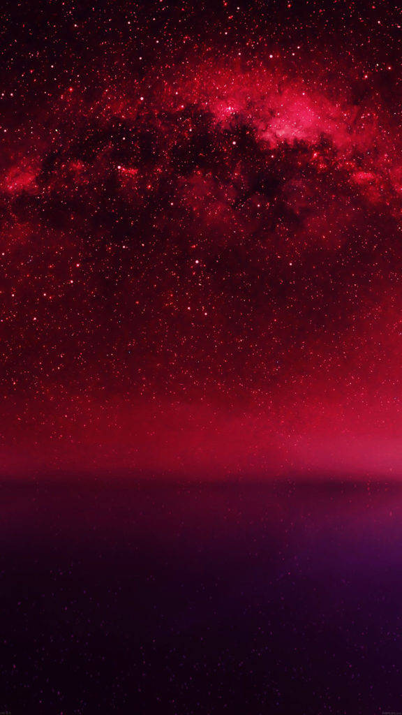 紅色星空 iPhone 活動壁紙 壁紙 — 在黑暗地平線上方，一個星系散發著深紅和紫色光芒的壯麗景色。
