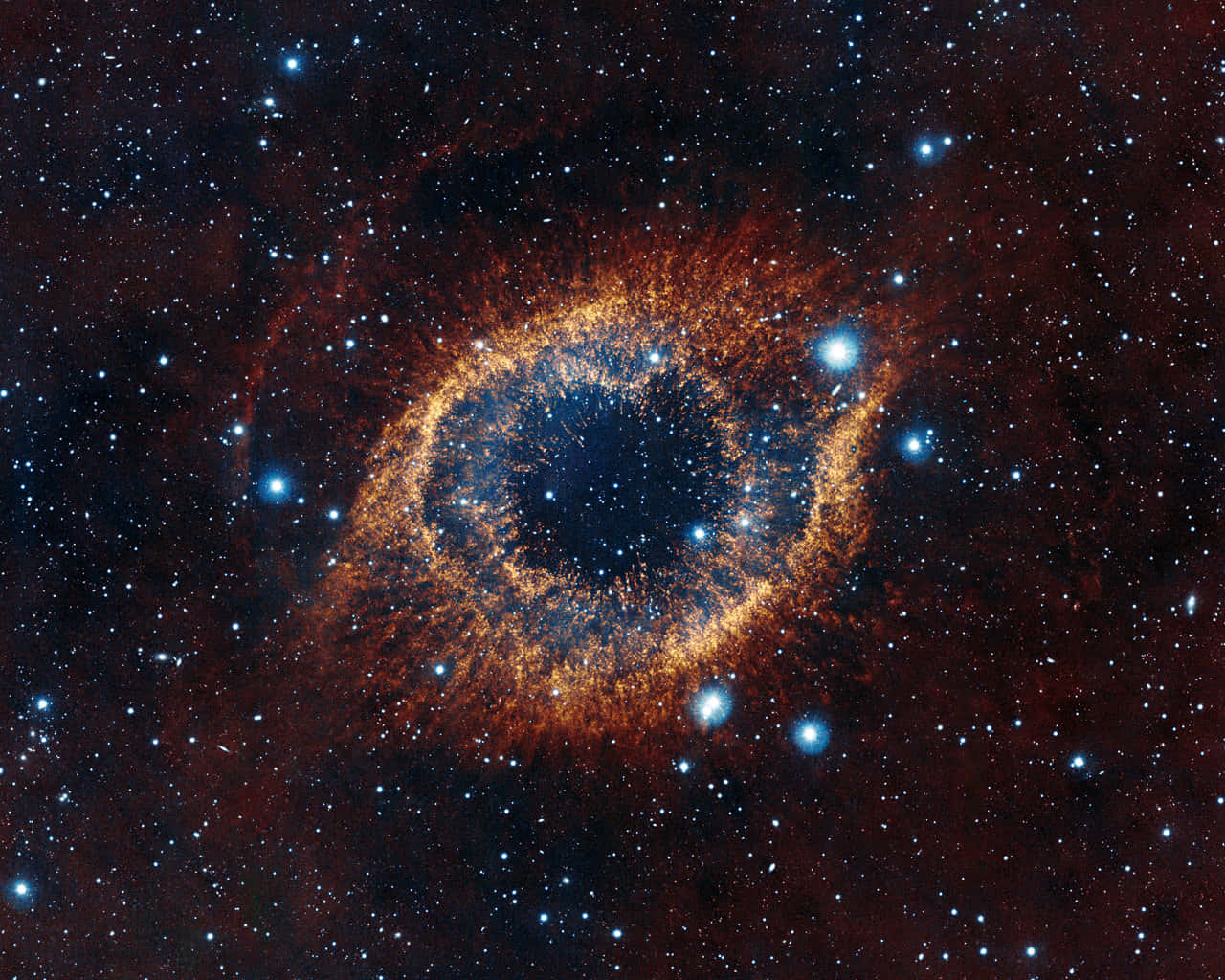 紅色星雲天文攝影 壁紙 — 一個宇宙眼睛星雲，在廣闊黑暗的太空中，被無數恆星包圍，散發出火熱的橙色和深藍色色調。