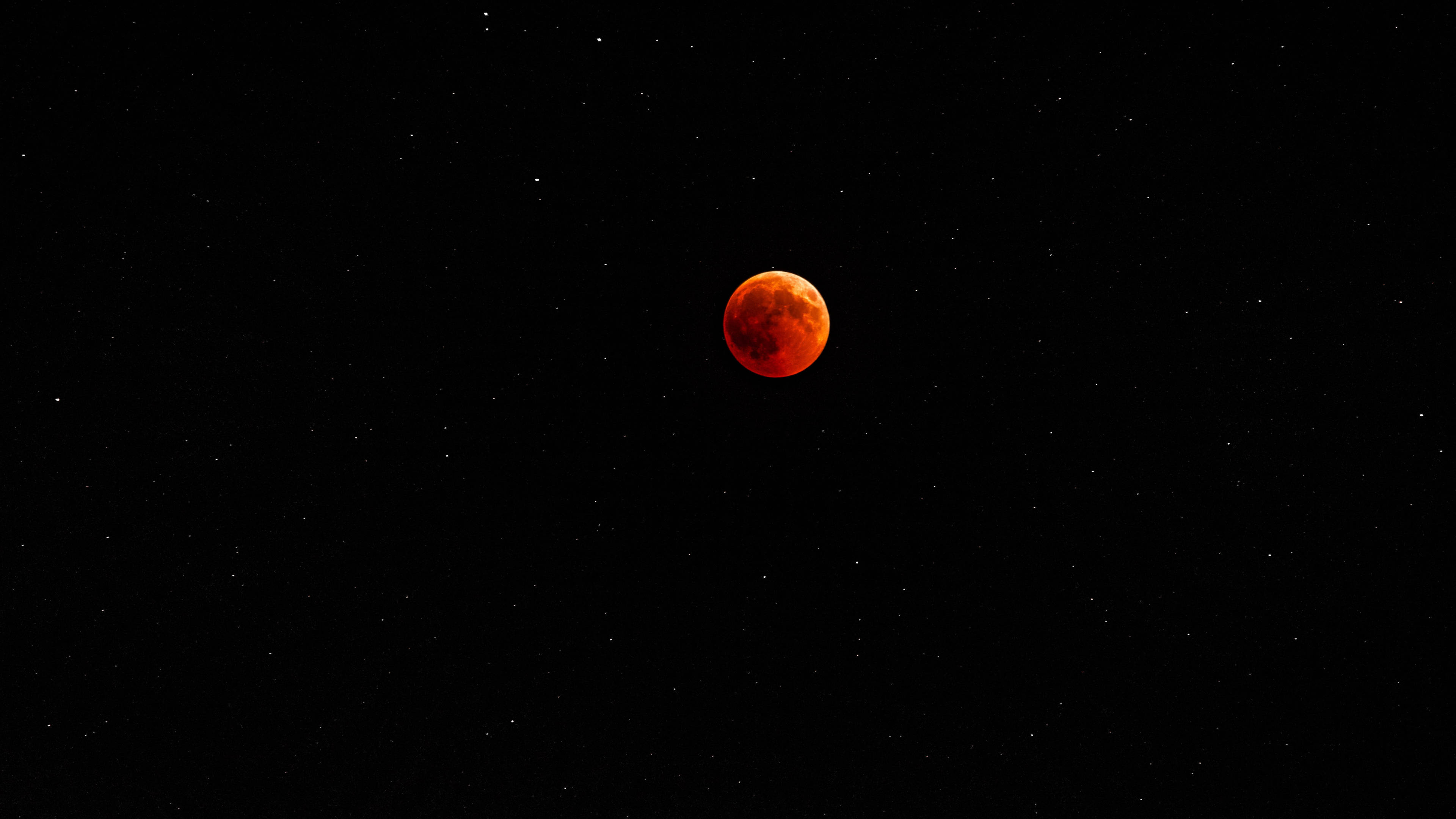 紅色月光 4K 壁紙 — 血紅月亮在繁星點點的黑色夜空中閃耀，形成天體月食。