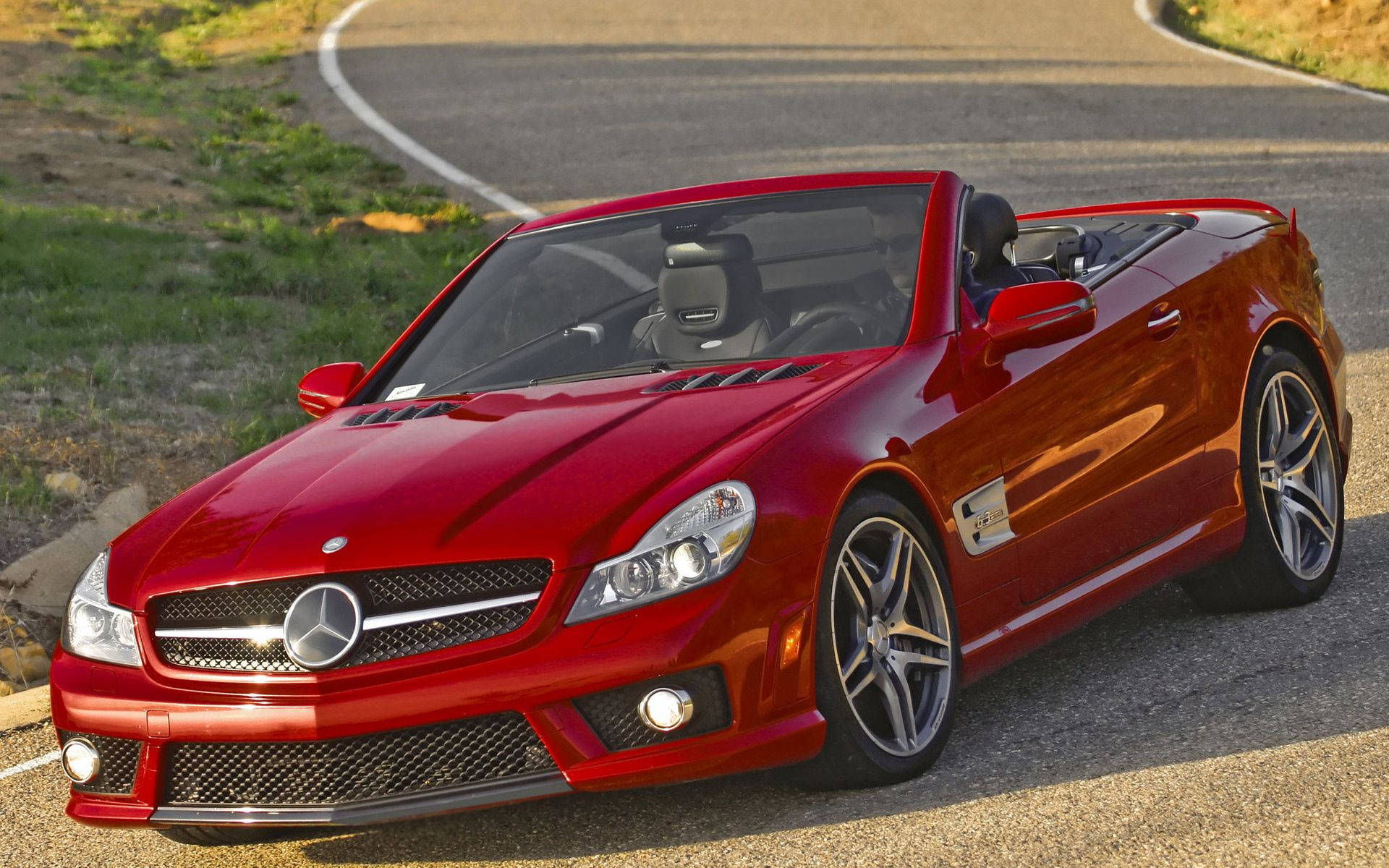 紅色Mercedes-Benz SLR McLaren開篷車停泊在日落時分的彎曲道路上。