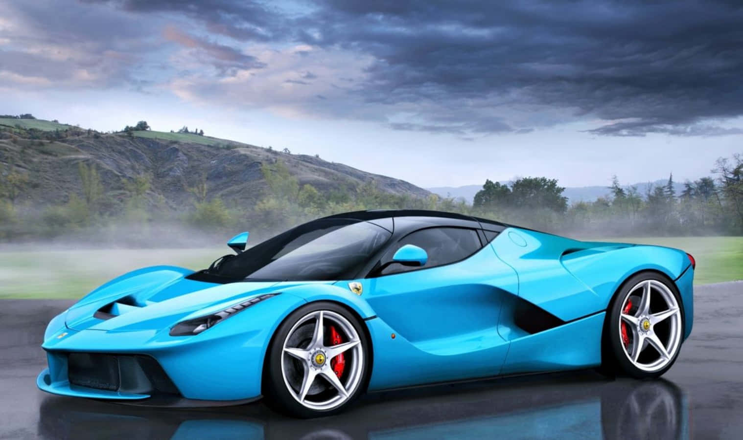 充滿活力的藍色法拉利 LaFerrari 在潮濕的道路上，背景有霧氣瀰漫的山丘和多雲的天空。