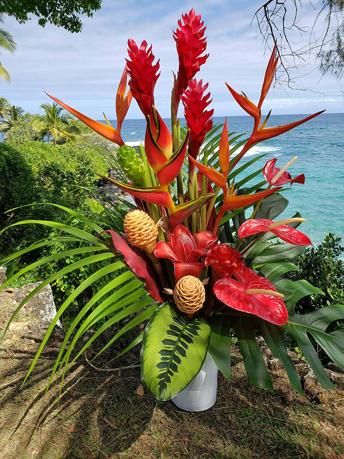 海邊的熱帶花卉佈置，搭配綠色葉片和藍色海水。