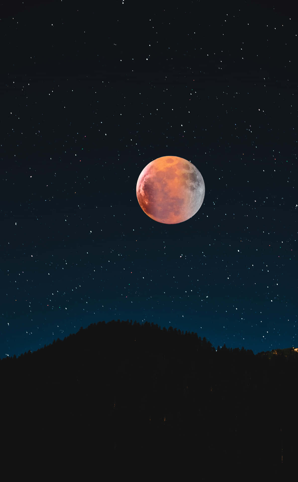 紅色滿月手機背景 壁紙 — 血月在繁星點點的夜空下，在黑暗的森林山丘上發出橙色和紅色的光芒。