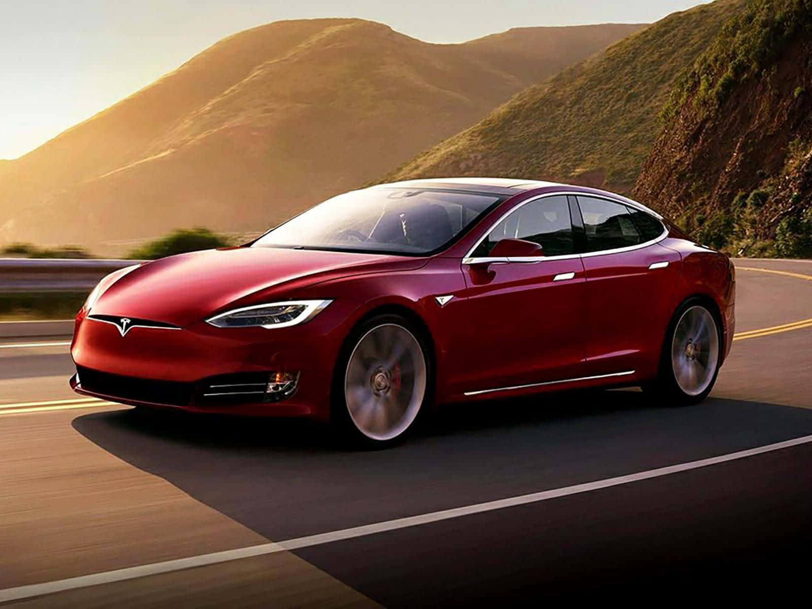 紅色Tesla Model S在日落時分在山區高速公路上飛馳。