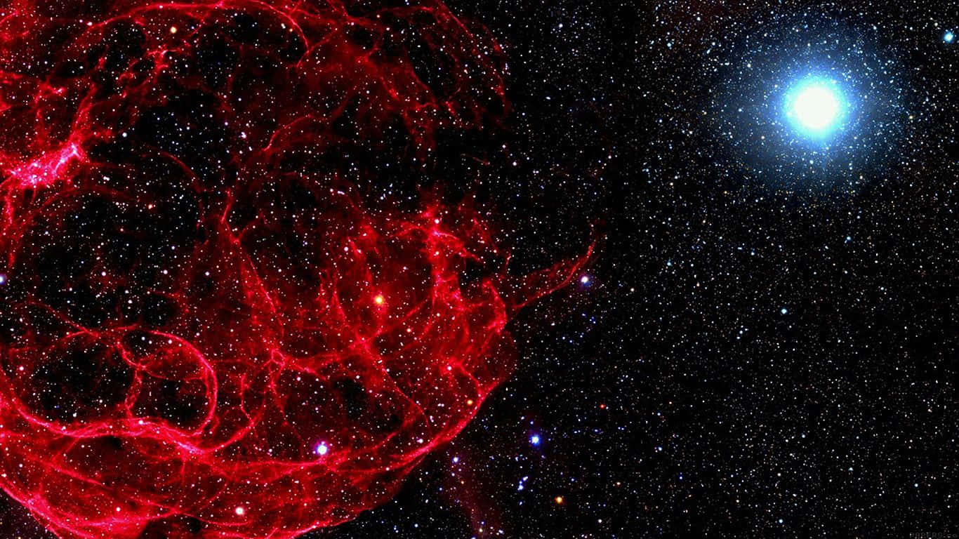 紅色美學筆記型電腦：麵包麵團星雲 壁紙 — 一片充滿活力的紅色星雲在星場中旋轉，遠處有一顆明亮的藍色星星閃耀。
