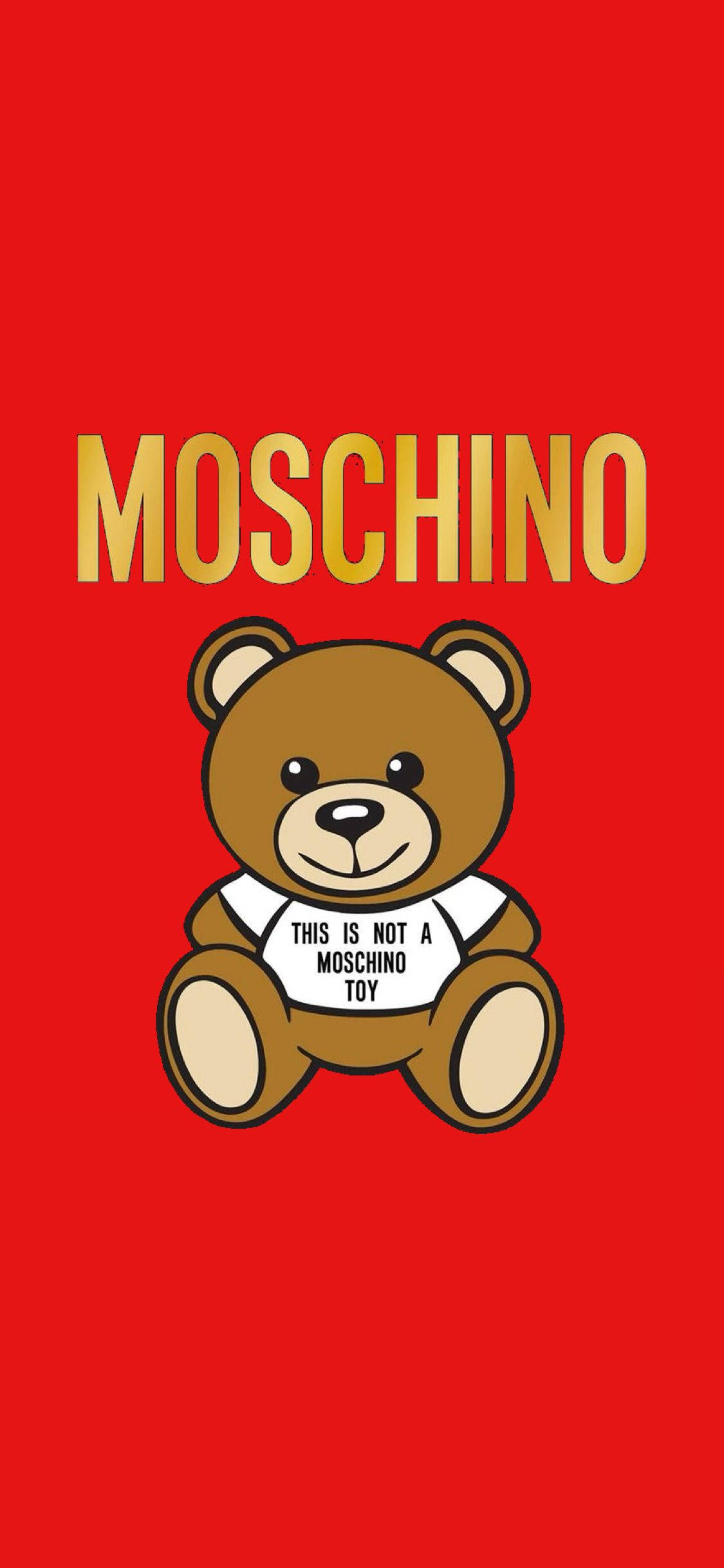 紅色背景Moschino泰迪熊 壁紙 — 一隻卡通泰迪熊穿著帶有文字的白襯衫，坐在大膽的紅色背景中央，上方有金色 'MOSCHINO' 字樣。