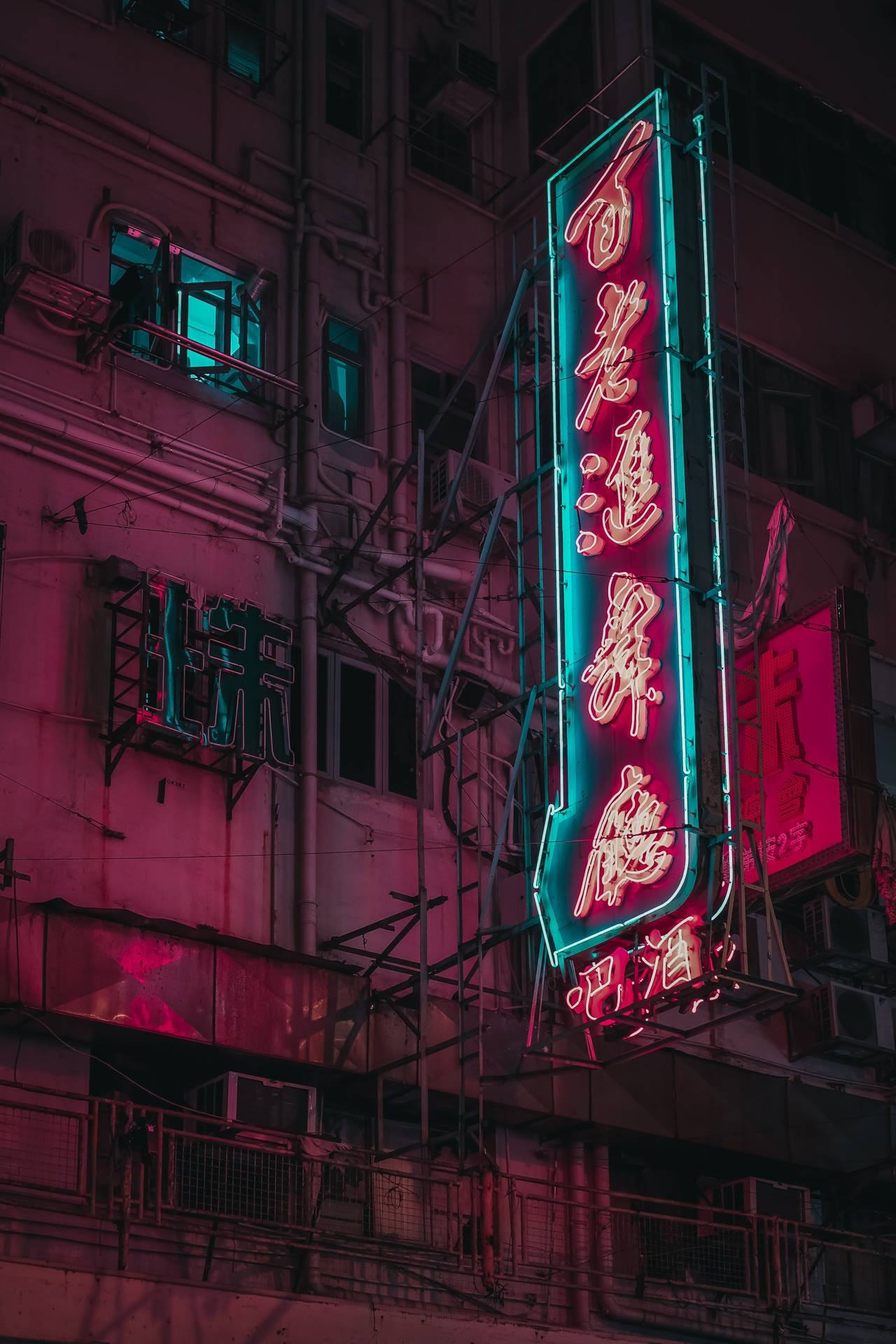 霓虹燈在夜間用粉紅色和藍綠色的色調照亮密集的城市建築。