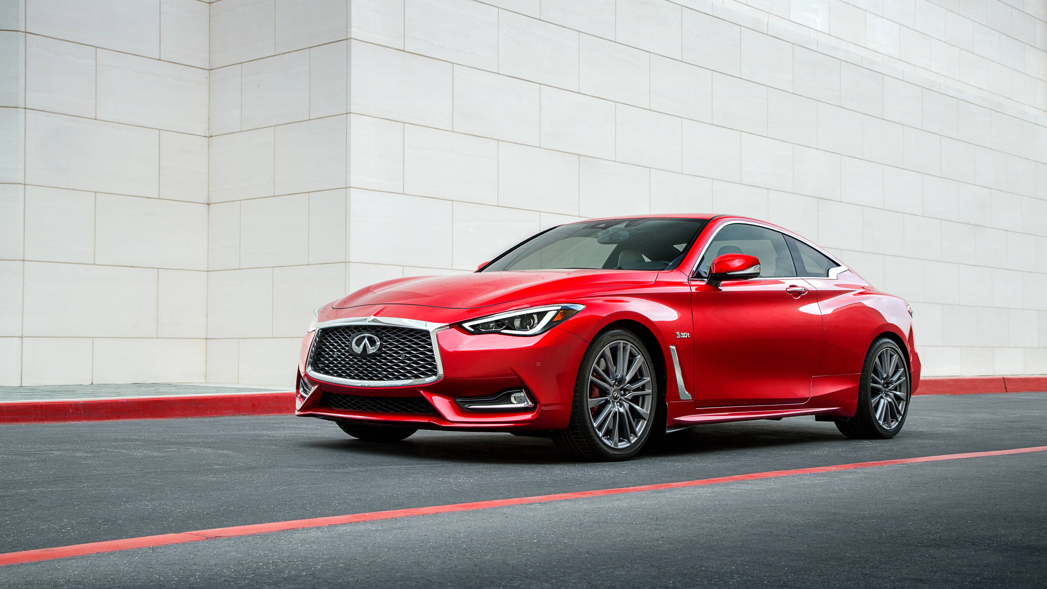 紅色英菲尼迪Q60在路上 壁紙 — 一輛光澤的紅色 Infiniti Q60 運動轎跑車停在乾淨的白色瓷磚牆前，帶有紅色路緣石 accents。